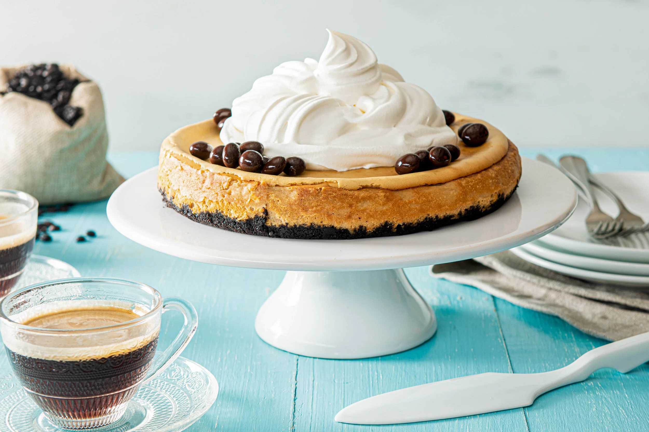 A cappuccino Cheesecake on a cake stand smothered in whipped cream and topped with espresso beans. Photography by Commercial Food Photographer, El Keegan, Dublin, Ireland.  