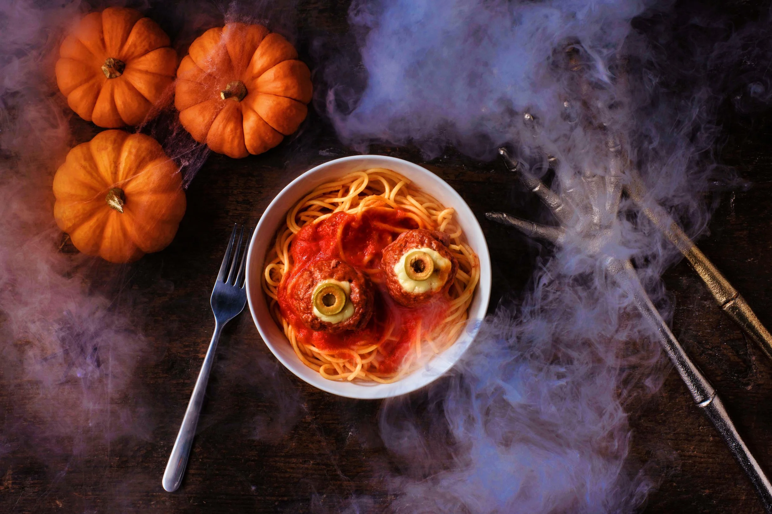  A spooky photo of spaghetti and meatballs dressed to look like eyeballs surrounded in smoke and halloween decorations. Food photography by El Keegan, Dublin.  