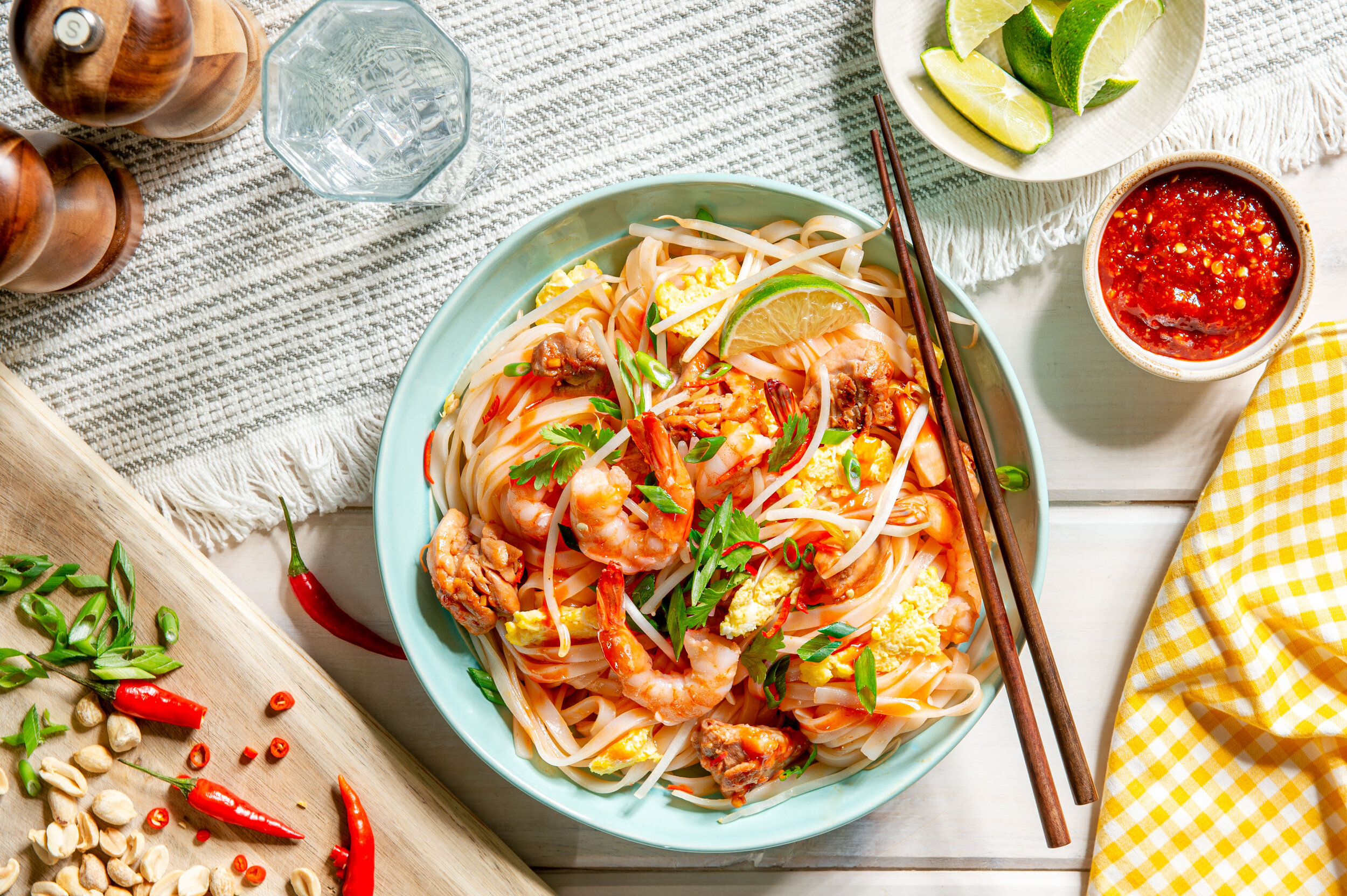  Prawn Pad Thai with noodles in a bowl with diced chillies and spring onions, lime wedge and a chilli sauce. Food Photography by El Keegan, Ireland.  