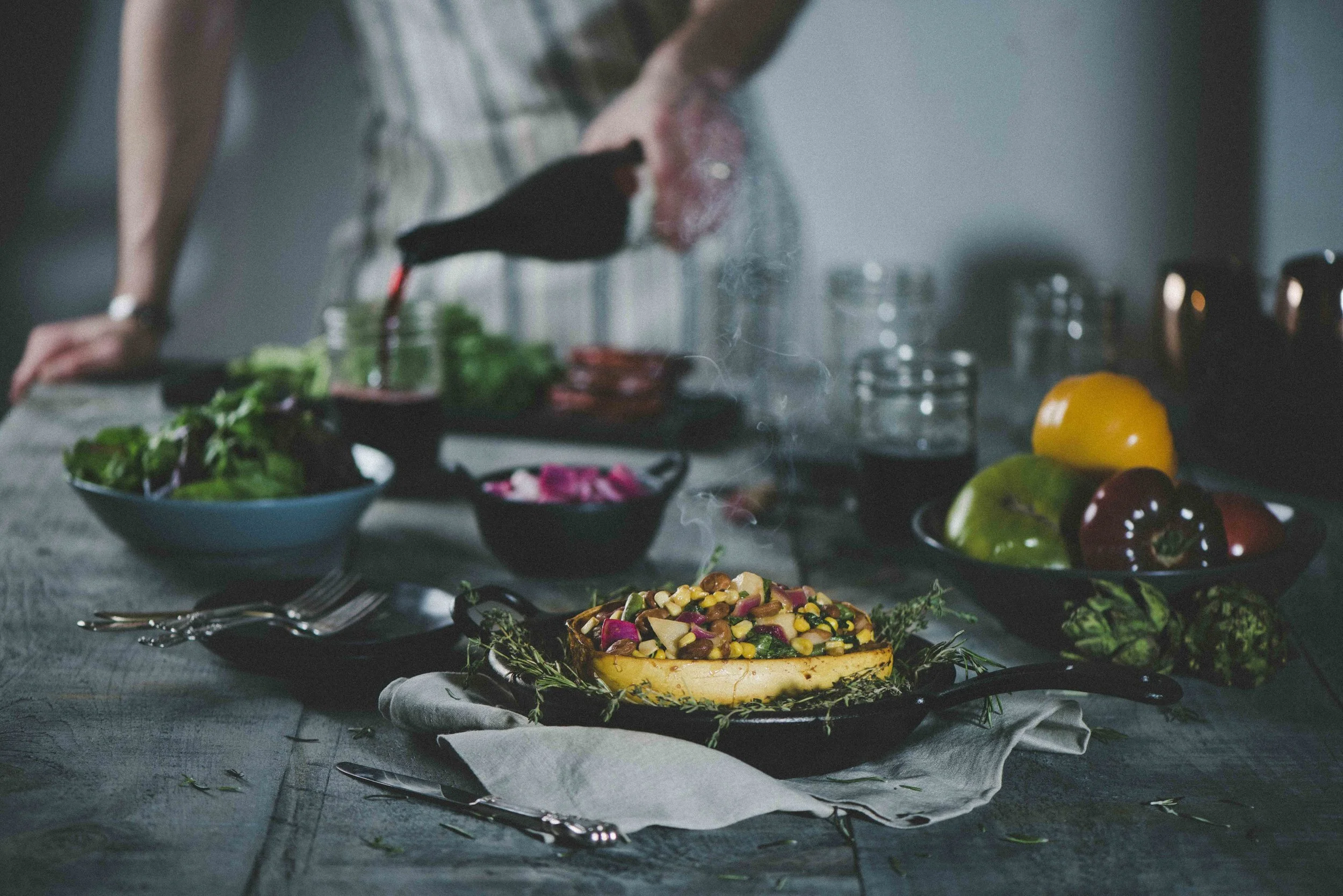  A chef pours a glass of wine behind a large decadent food spread on a harvest dinner table. Photography and Retouching by El Keegan, Ireland.   