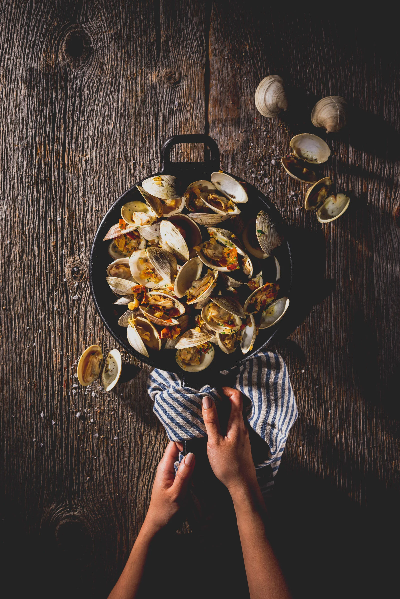  A dark moody food photo of a cast iron pan, wrapped in a tea towel, holding mussles. Photography by El Keegan, Dublin, Ireland.   