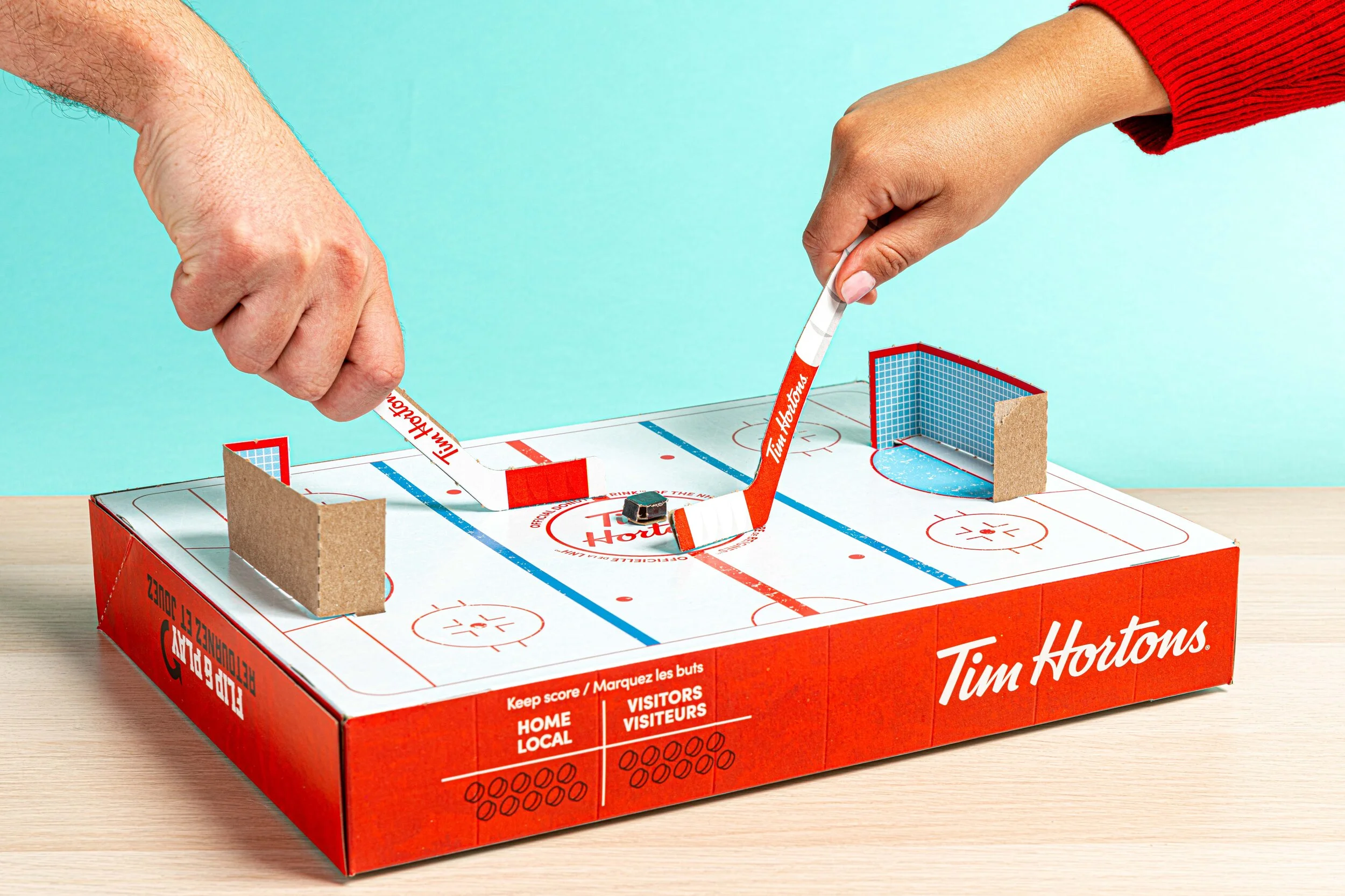  Two people play cardboard hockey on a Tim Hortons donut box. Commercial Photography by El Keegan.  