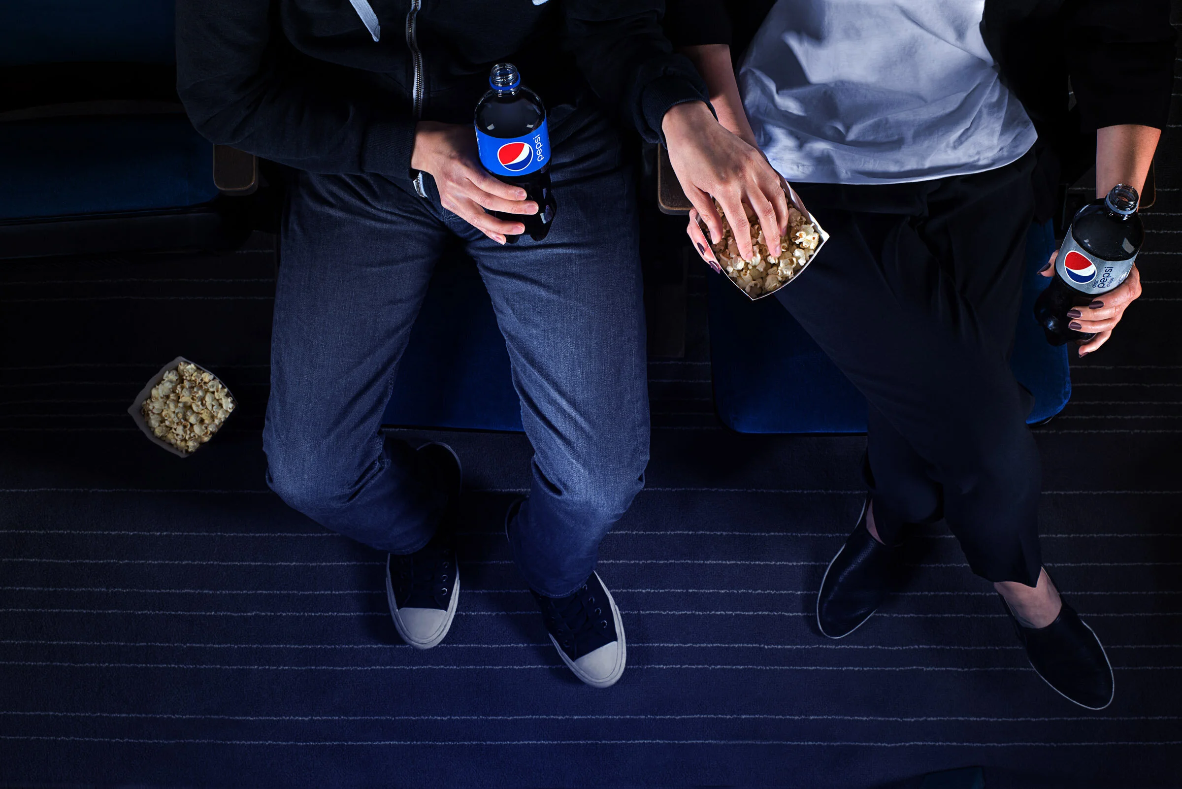  A couple enjoy a bottle of Pepsi each while sharing popcorn in a cinema. Commercial Photography by El Keegan, Dublin.  