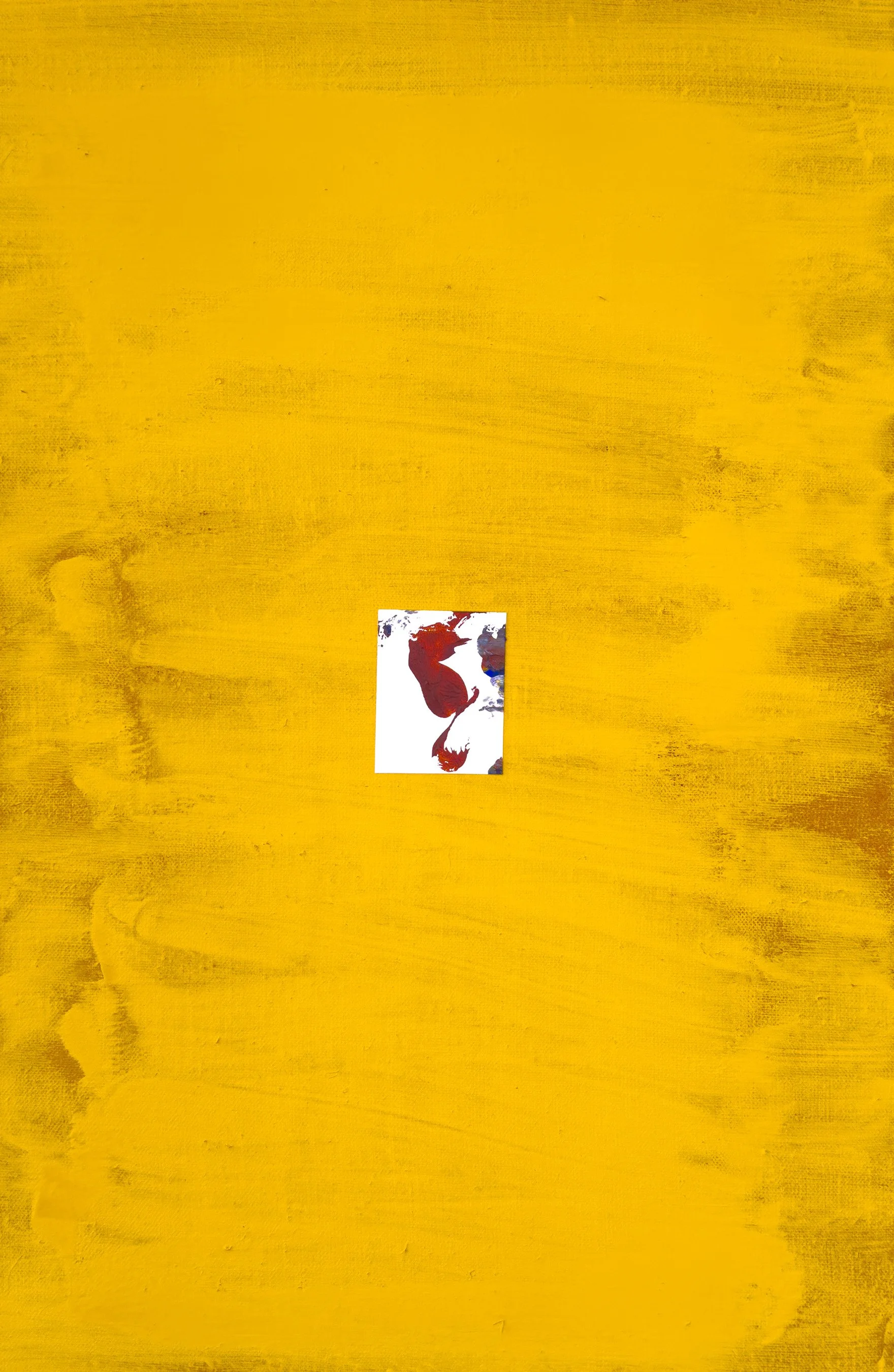 Photograph of a yellow painted wooden surface with a small rectangular card featuring red and brown paint strokes placed near the bottom center.