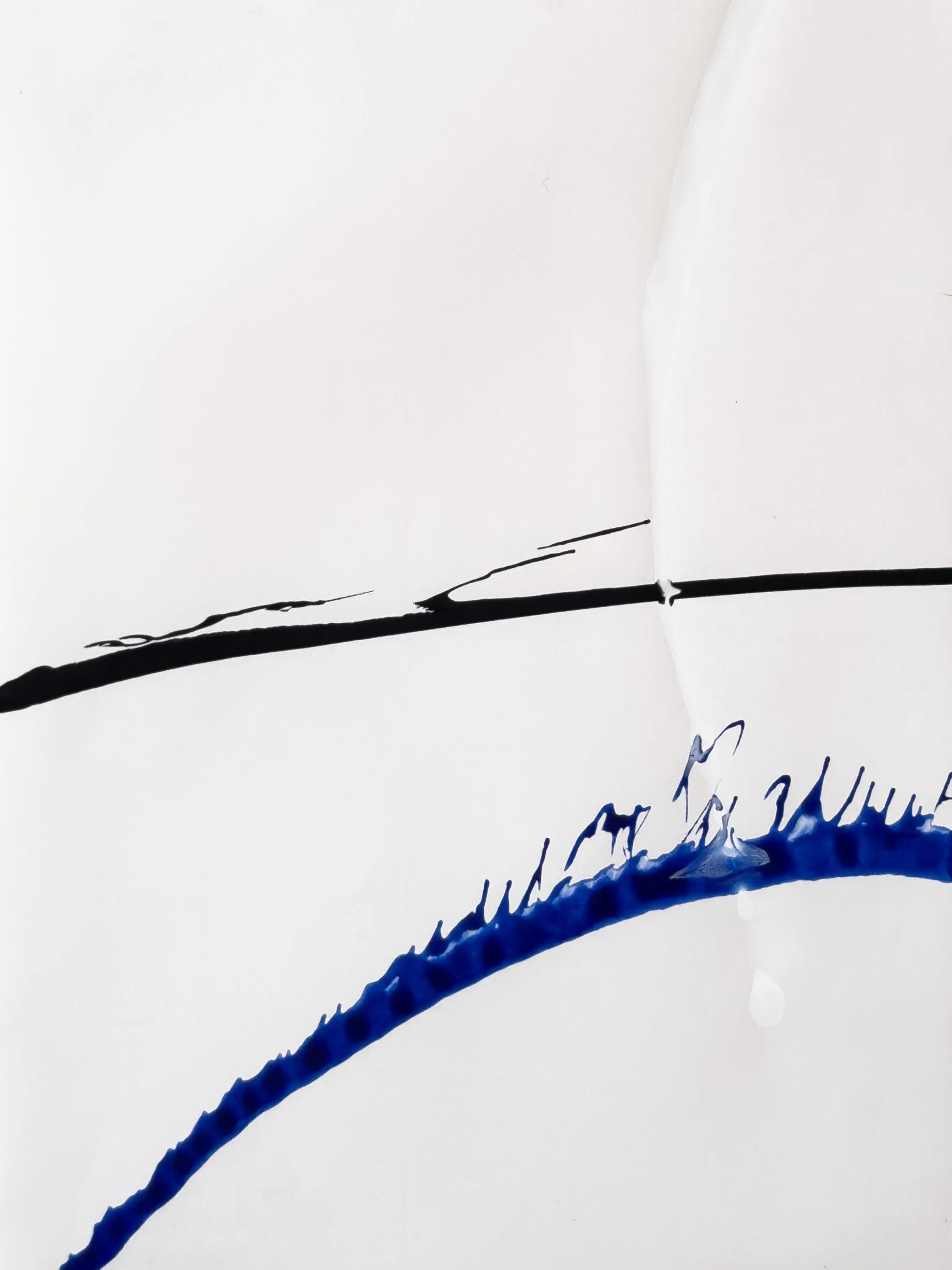 Close-up of abstract black and blue ink strokes on white paper, with some handwritten blue text visible at the bottom.