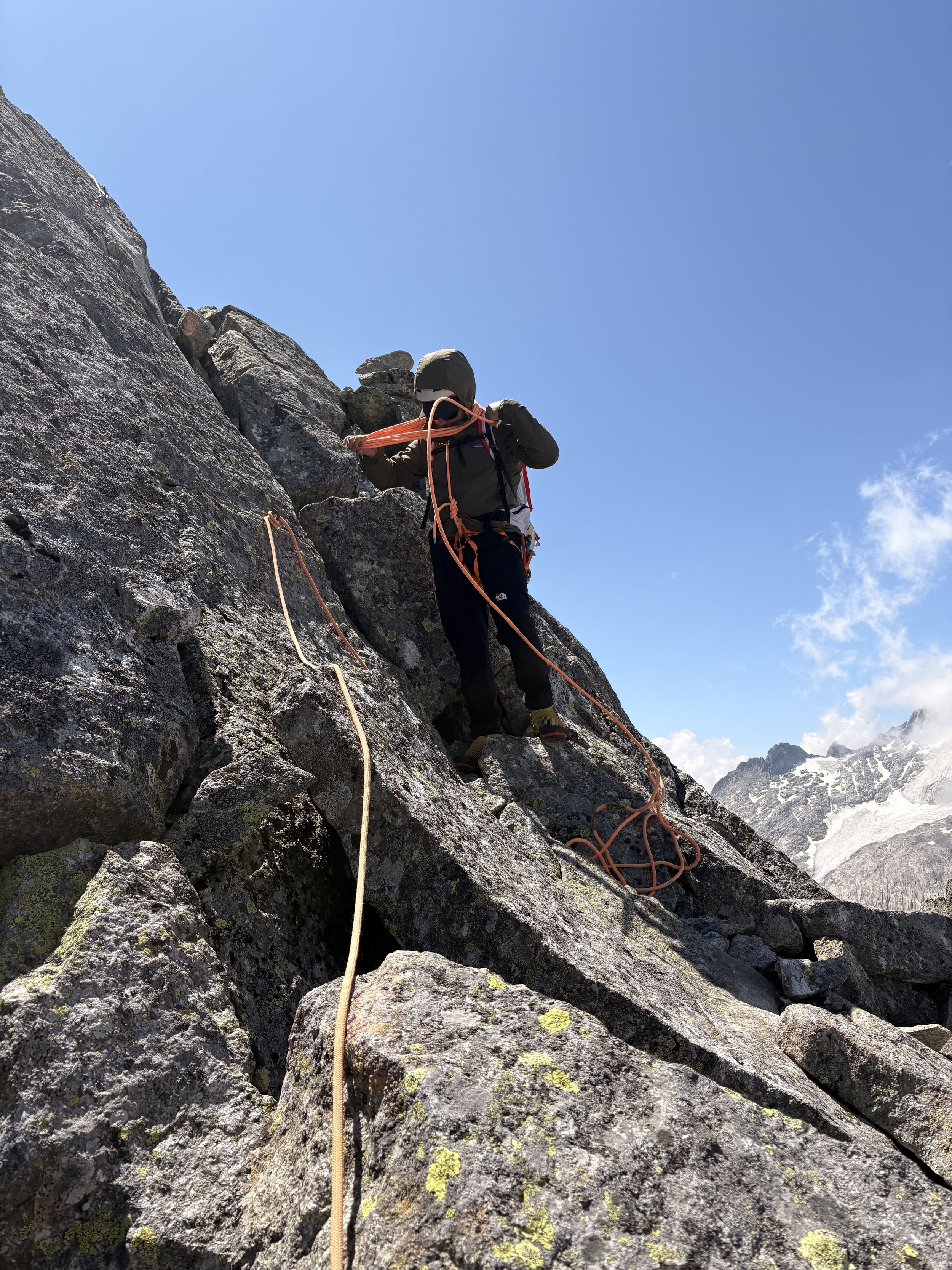 Kletterer auf felsiger Bergwand in den Bergen unter blauem Himmel.