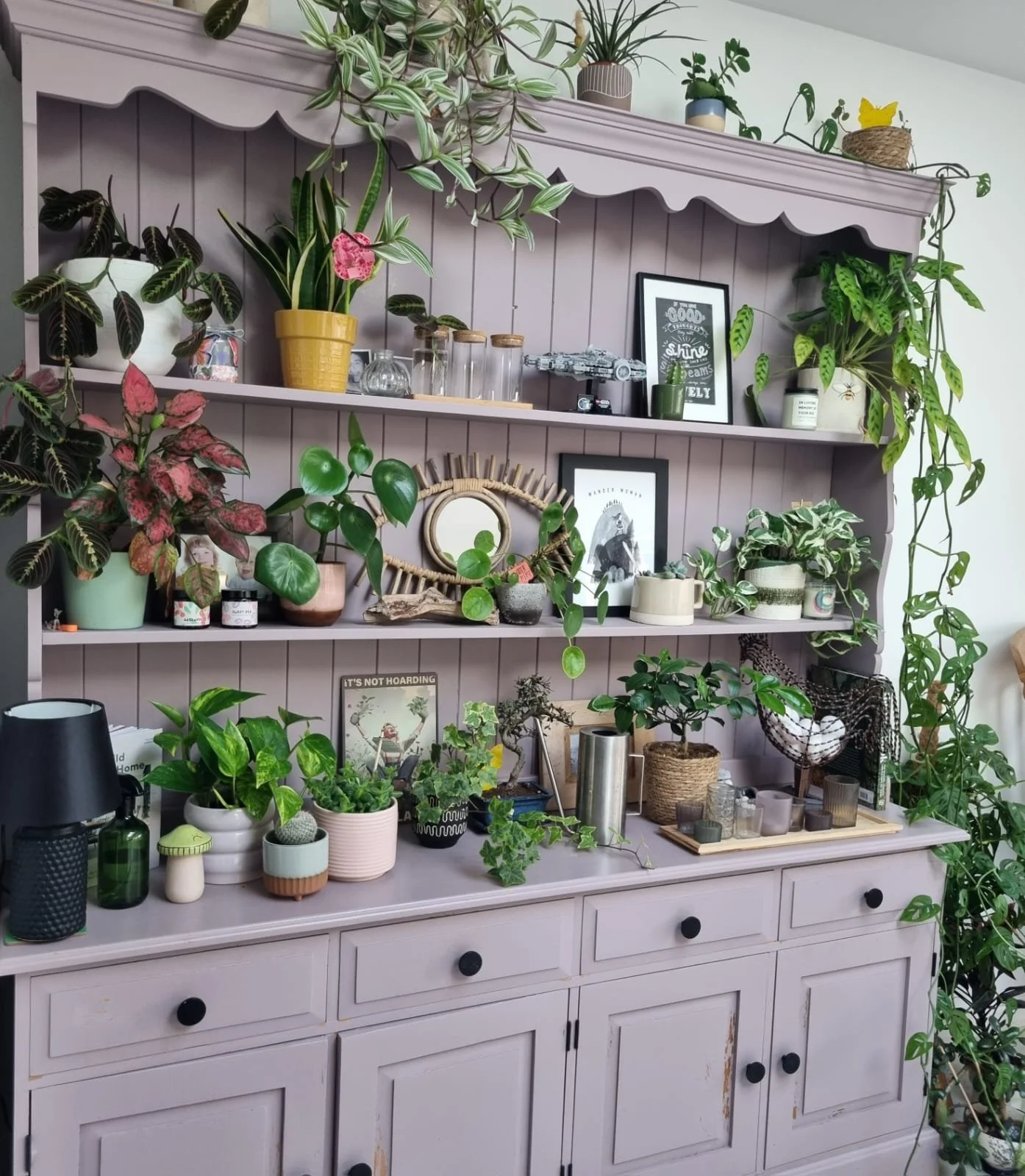 A pale purple wooden hutch filled with various potted plants and decorative items.