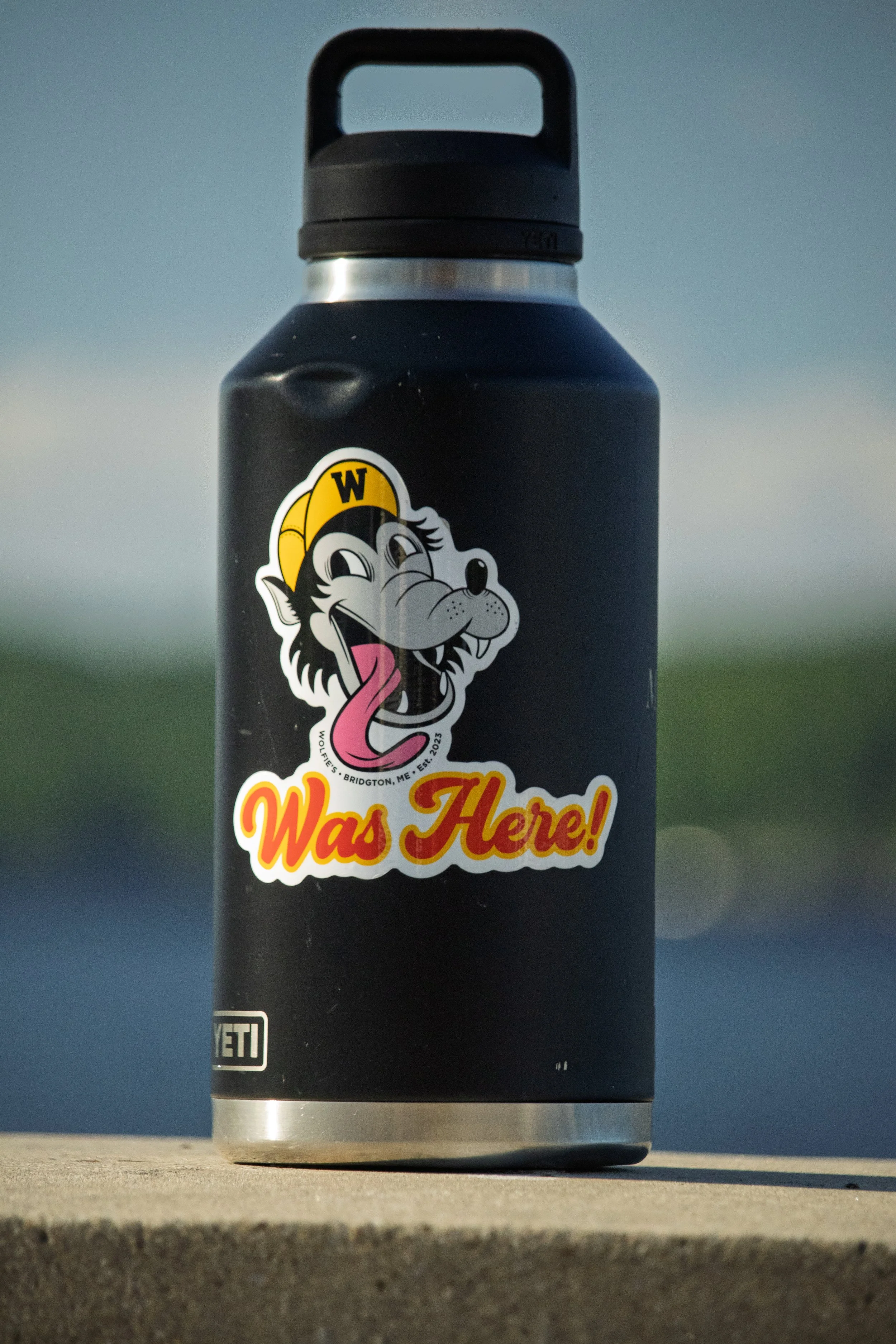 A black water bottle with a cartoon wolf - Wolfie's Located in Bridgton, Maine