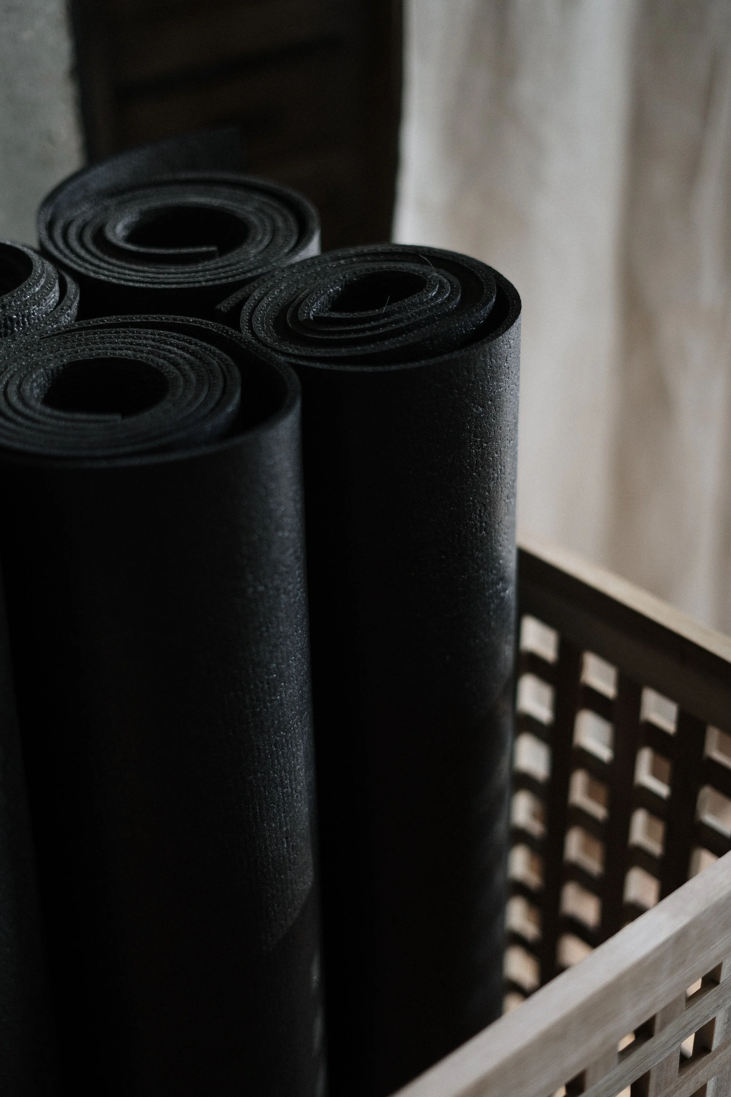 Tapis de Pilates noirs rangés dans un panier.
