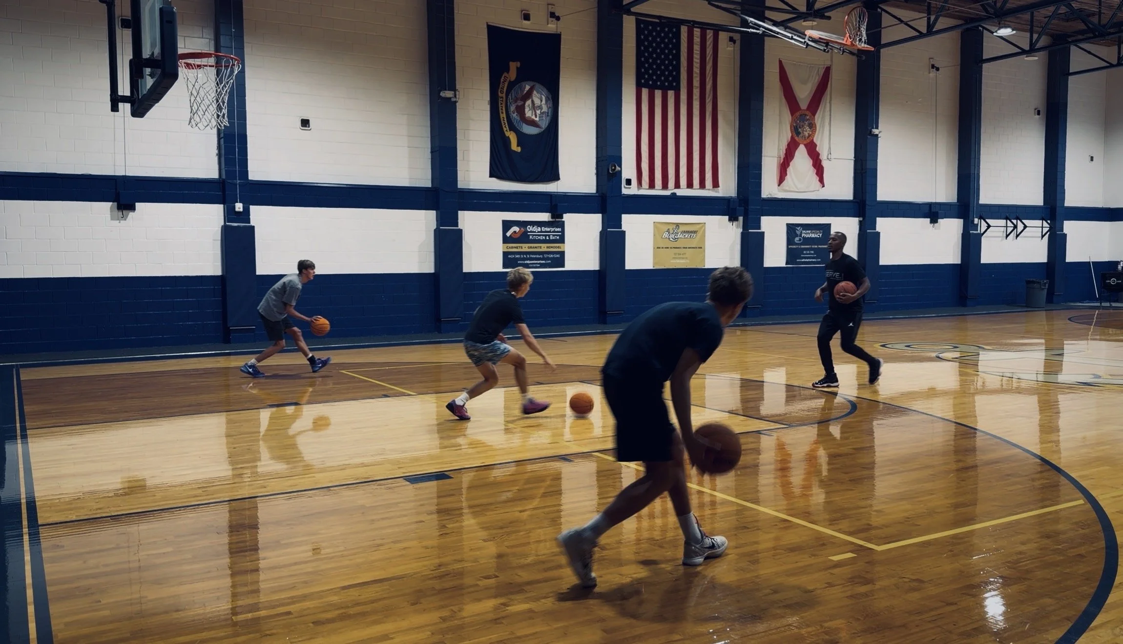 A small group of high school players practicing basketball drills in an indoor gym in Saint Petersburg, FL