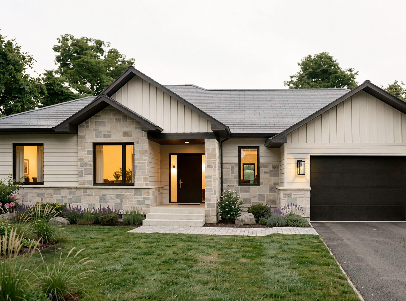 Maison moderne avec façade en pierre et bois, entrée avec escaliers et jardin bien entretenu, garage attenant, éclairage extérieur, arbres en arrière-plan. Atelier Au Carré