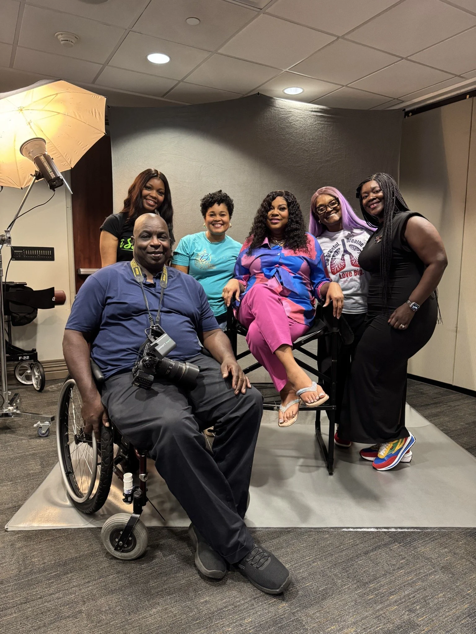 2nd Wind makeover event group, including a photographer seated in a wheelchair with his camera.