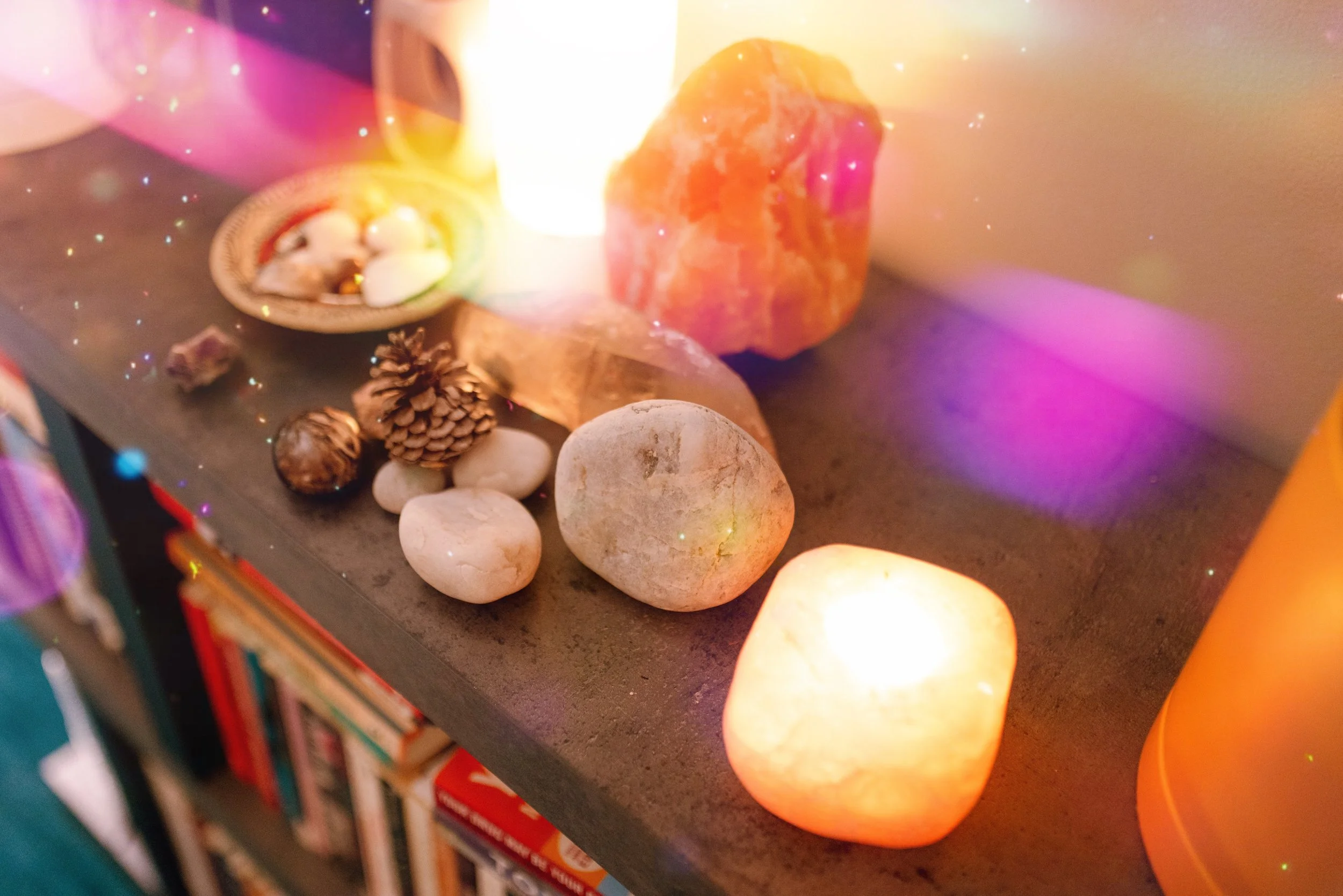 Salt rocks, pinecones, and candles on a shelf with lights and a blurred bookshelf in the background.