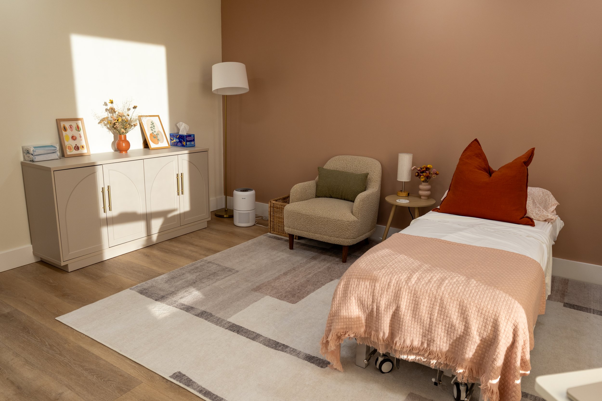 Cozy treatment area at Terra Pelvic Health with natural lighting, a comfy chair, and a comfortable treatment table