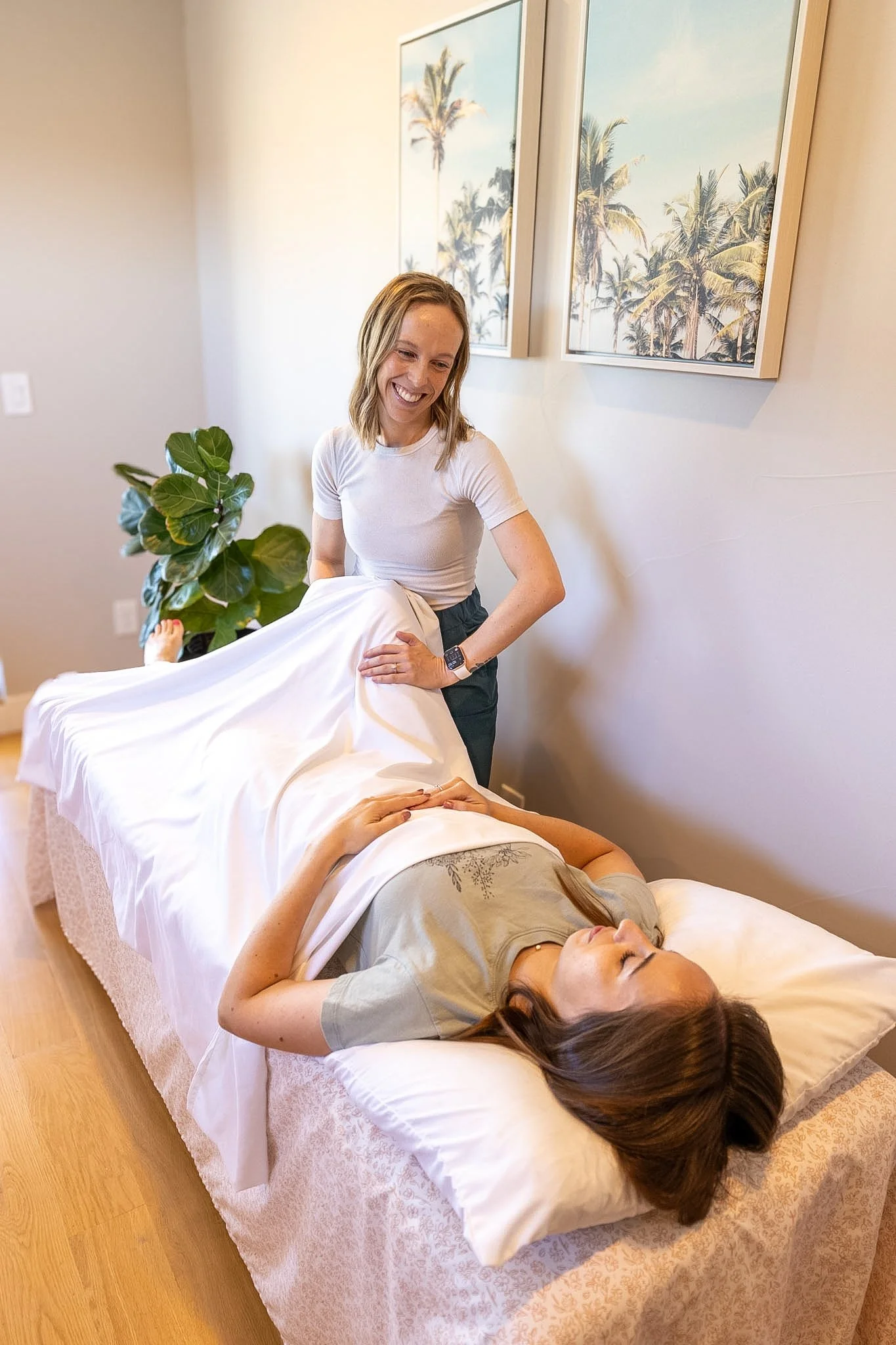 A woman lies with her eyes closed, receiving expert care from a pelvic floor therapist. The room is cozy with soft natural lighting.
