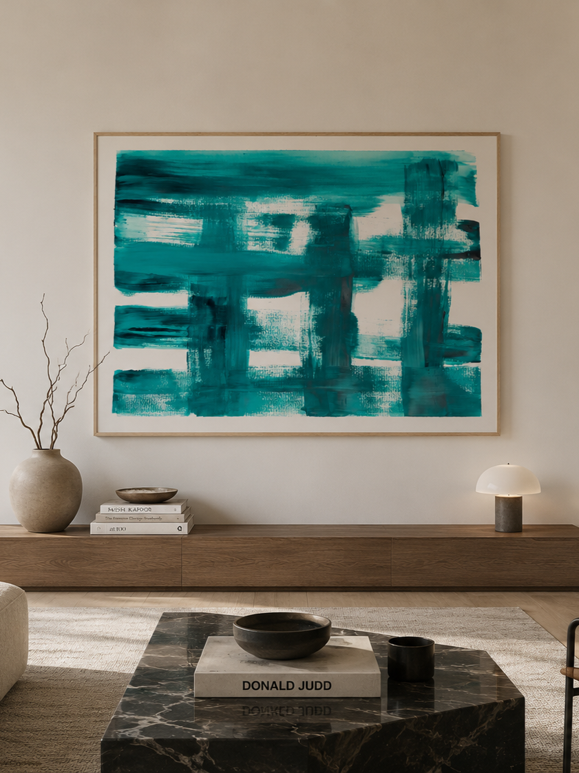Sala de estar decorada con pintura abstracta en colores azul y verde en la pared, mesa de mármol negro con libros y objetos decorativos, lámpara moderna, y jarrón con ramas secas.