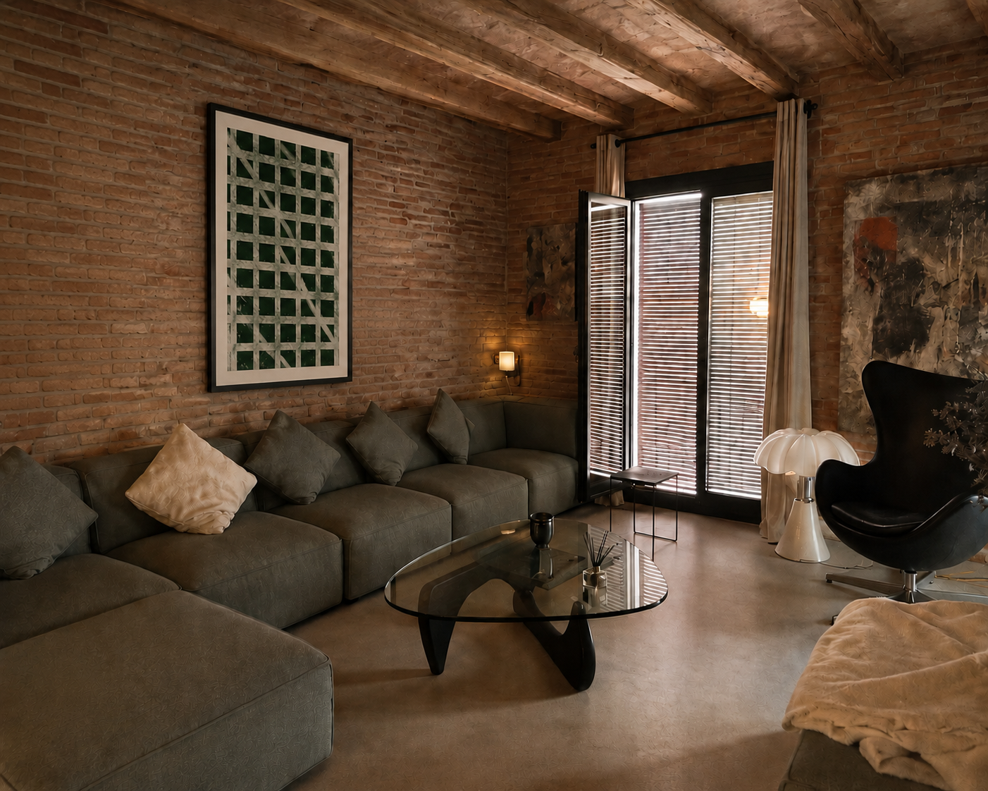 Sala de estar con muro de ladrillos, un sofá grande con cojines, una mesa de vidrio, una lámpara de ambiente, una silla negra tipo huevo, y puertas con persianas de madera que dejan entrar la luz natural.