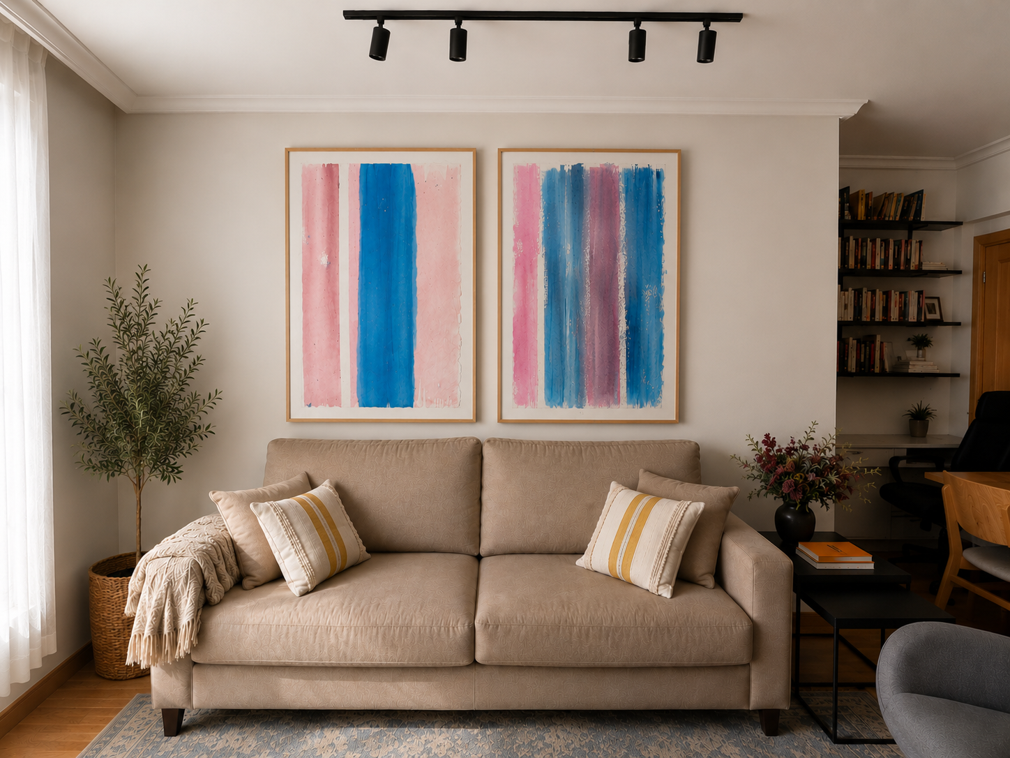 Sala de estar con un sofá beige, dos cuadros abstractos en tonos rosas y azules en la pared, plantas decorativas y estantería con libros.
