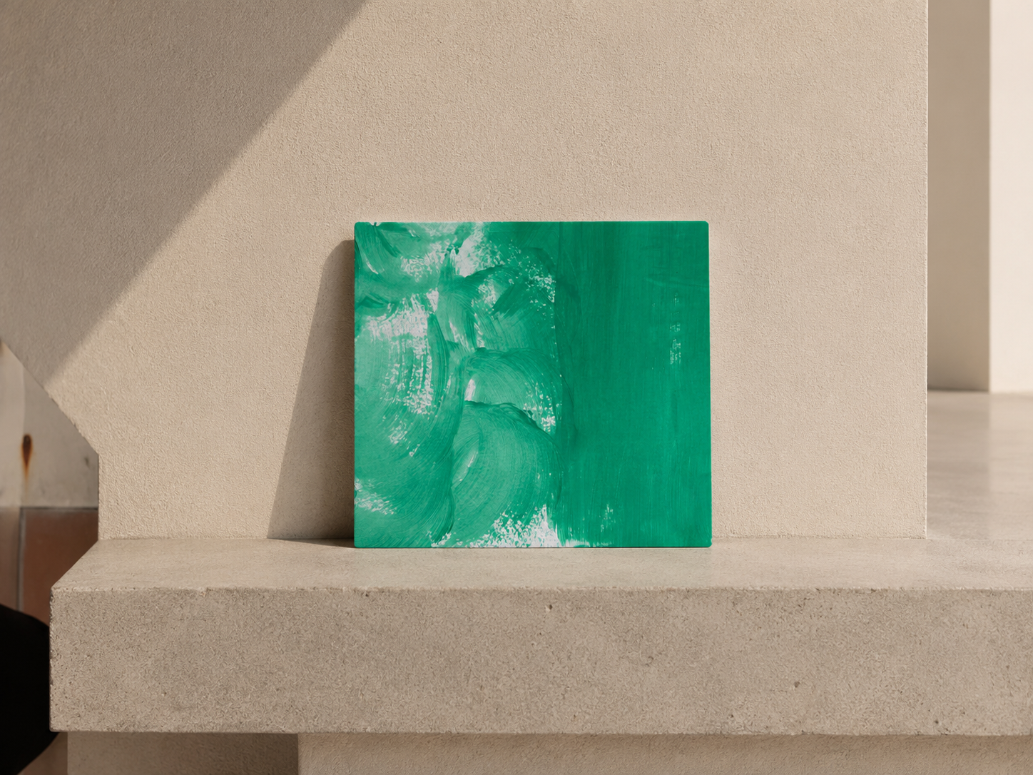 Cuadro abstracto con tonos verdes en una pared beige.