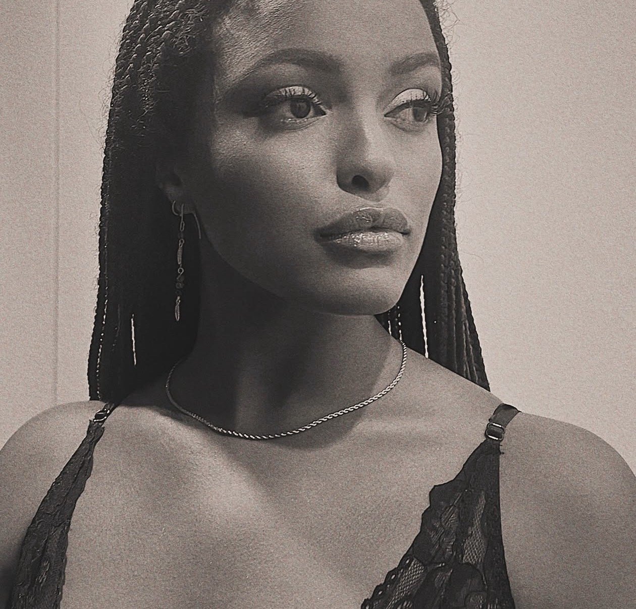 Retrato en blanco y negro de una mujer con peinado de trenzas, usando aretes largos, collar y vestido de encaje