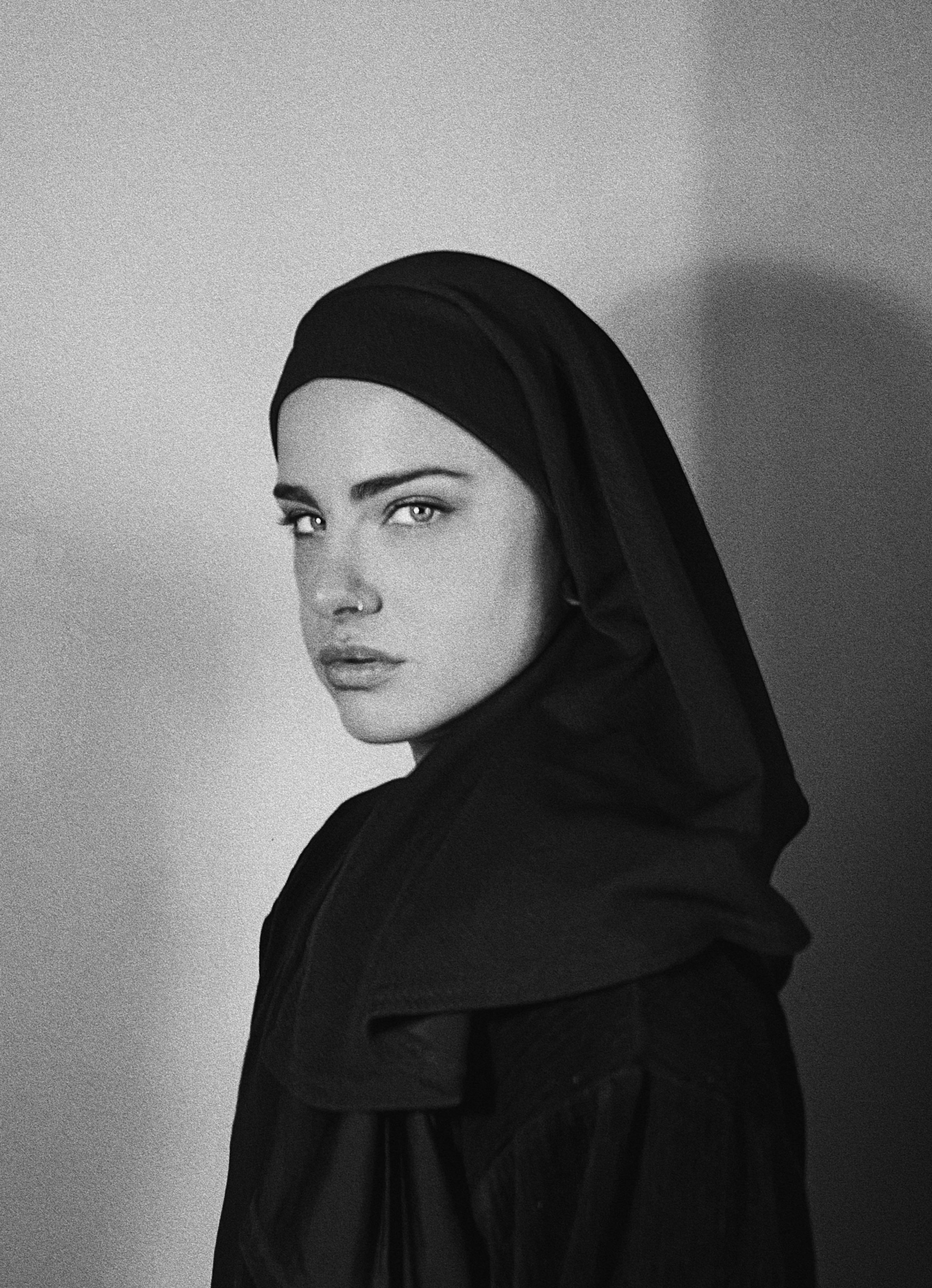 Retrato en blanco y negro de una mujer con un velo negro en la cabeza, mirando hacia la cámara.