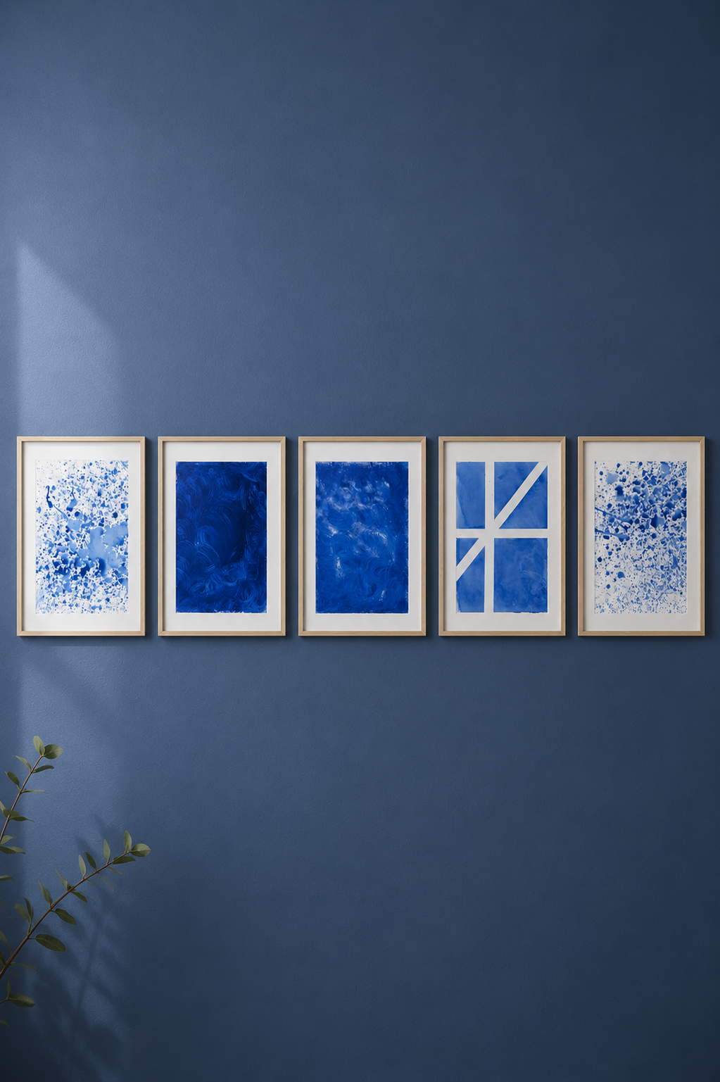 Cinco marcos de cuadros con arte abstracto en tonos azules, colgados en una pared azul, con una planta en la esquina inferior izquierda.
