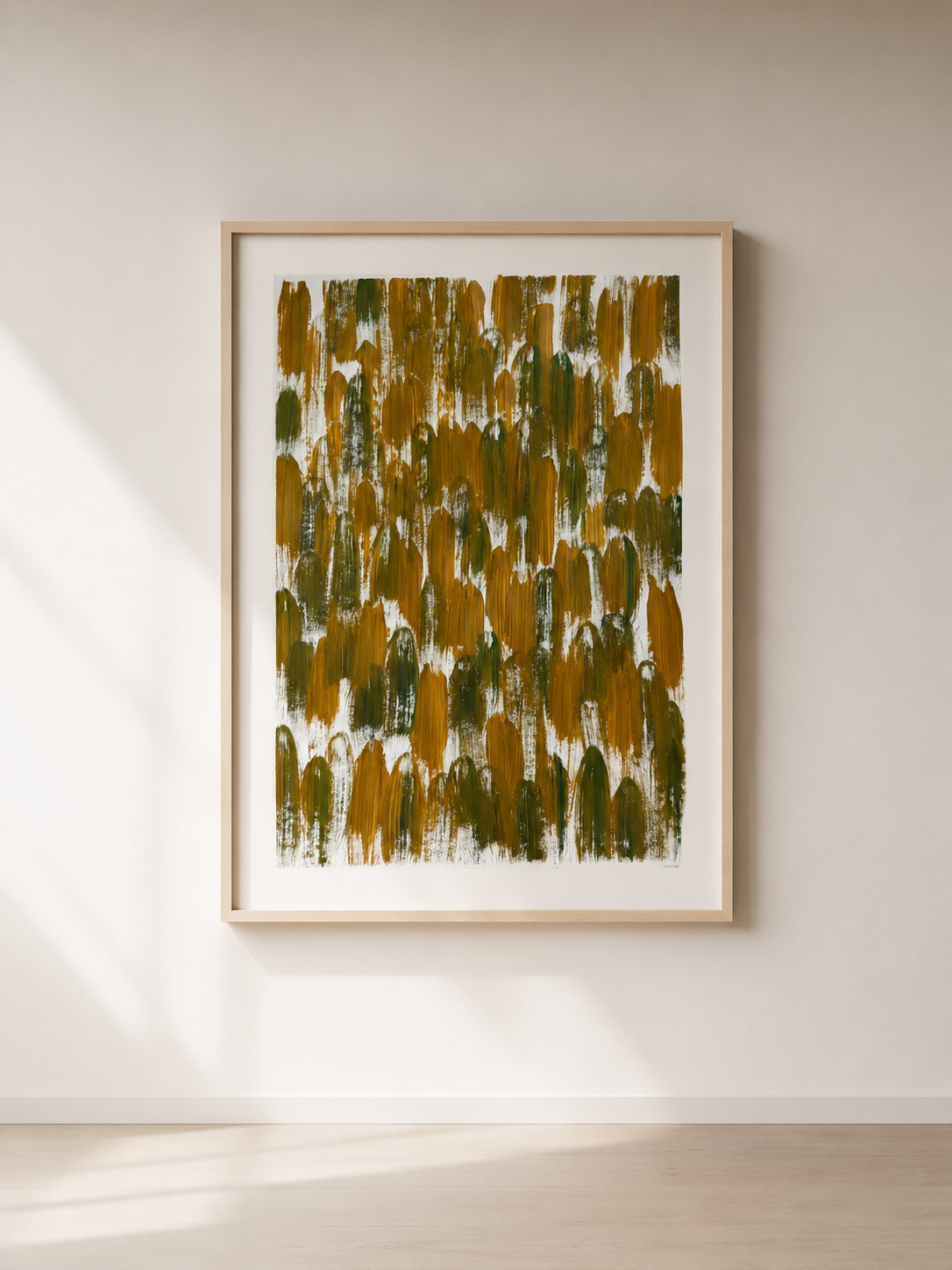 Cuadro abstracto con trazos en tonos verdes y amarillos enmarcado en madera clara, colgado en pared blanca