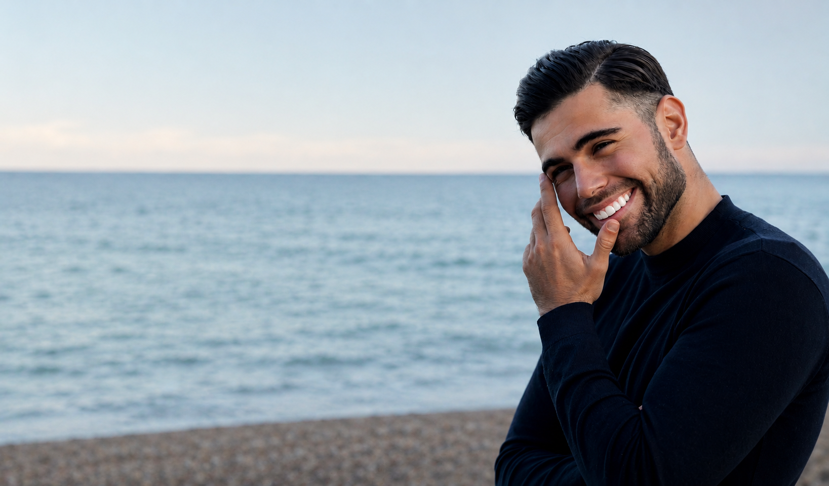 Joven sonriendo en la playa con el mar de fondo.