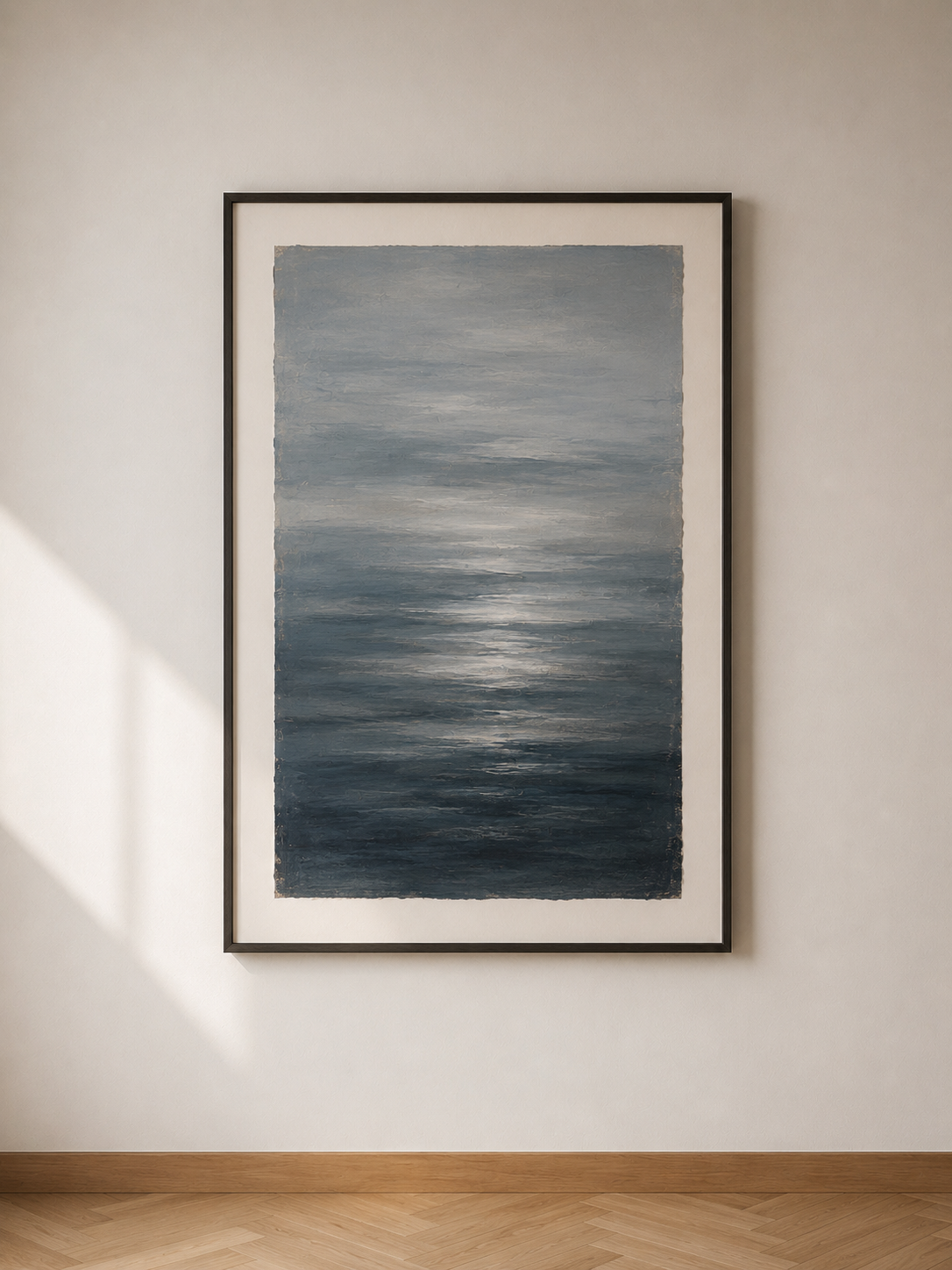 Cuadro con pintura abstracta de tonos azules y grises en un marco negro en una pared blanca con luz natural.