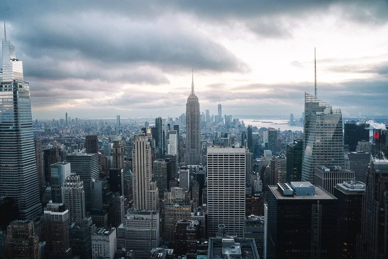 A view of New York City skyline with the Empire State Building in the center and overcast skies.