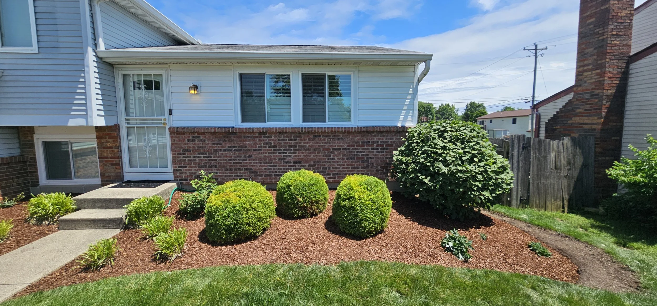 Fresh mulch installation and detailed bed cleanup around front foundation shrubs.