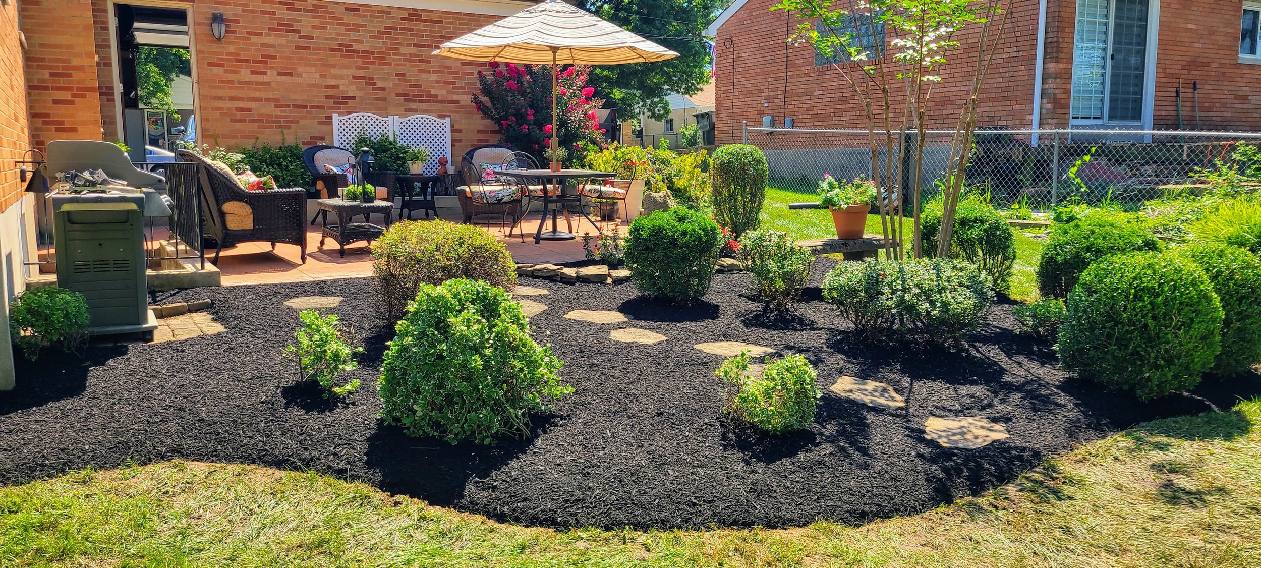 Maintained patio landscape beds with trimmed shrubs, dark mulch, and clean seasonal detail work.