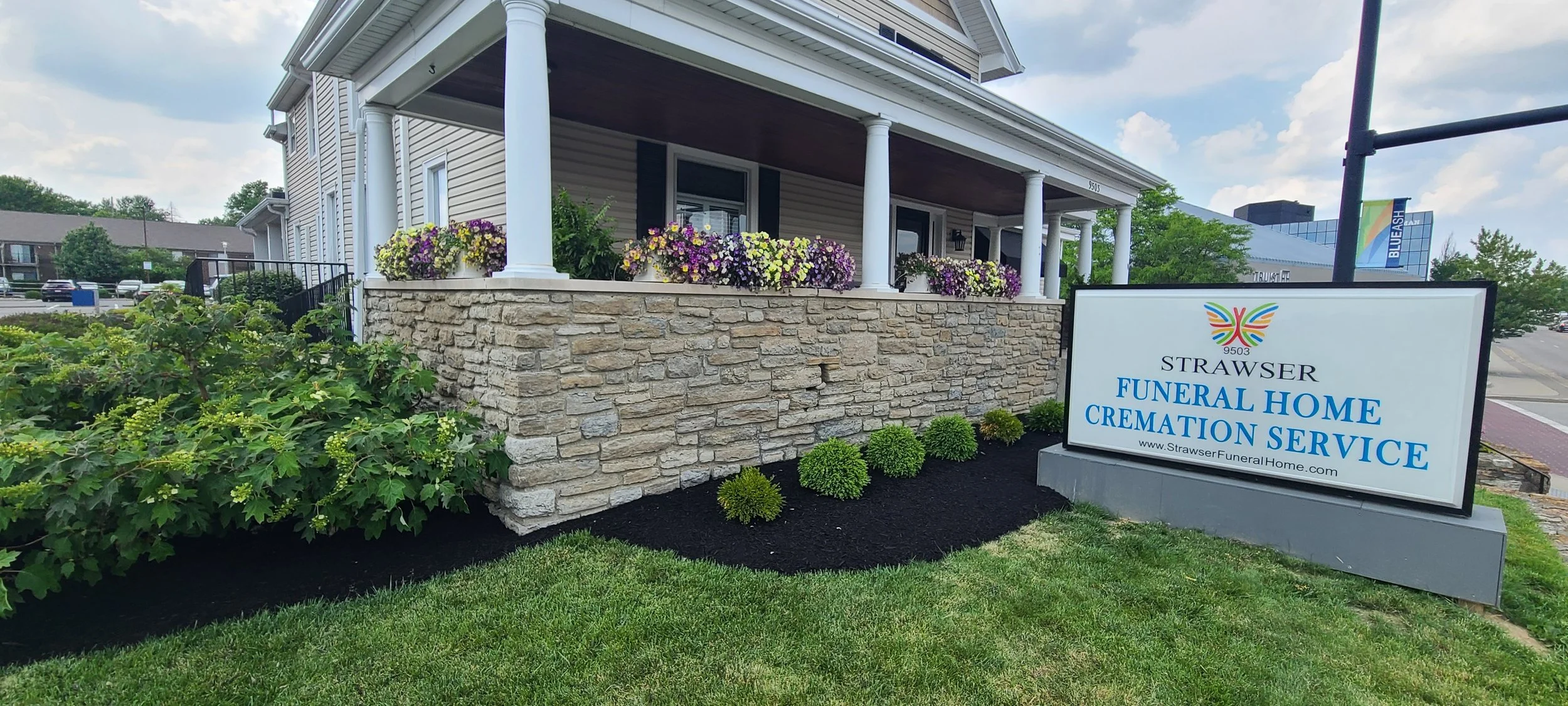 Maintained landscape beds with dark mulch and seasonal planting around a small local business property.
