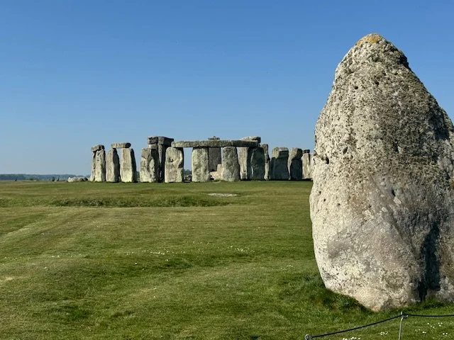 A picture of a Sarsen stone in the foreground with Stonehenge in the background