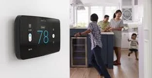 Digital thermostat showing 78°F on a wall in a modern kitchen with a family cooking and children present.