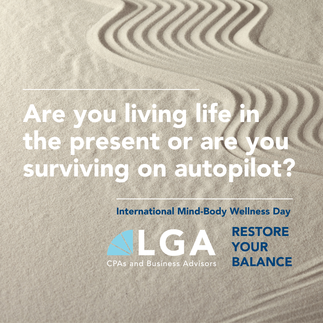 Sand dunes with wind patterns, overlaid with text asking if you are living in the present or surviving on autopilot, promoting International Mind-Body Wellness Day and emphasizing restoring your balance, with a logo for LGA CPAs and Business Advisors