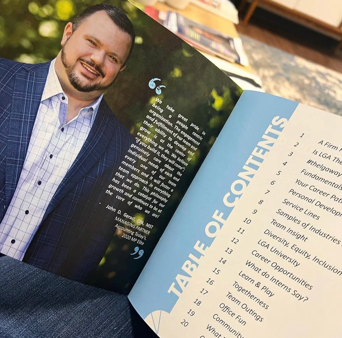 Open booklet showing a portrait of a man in a suit and text about team engagement on the left side, and a table of contents on the right side. The background includes a blurred outdoor scene.