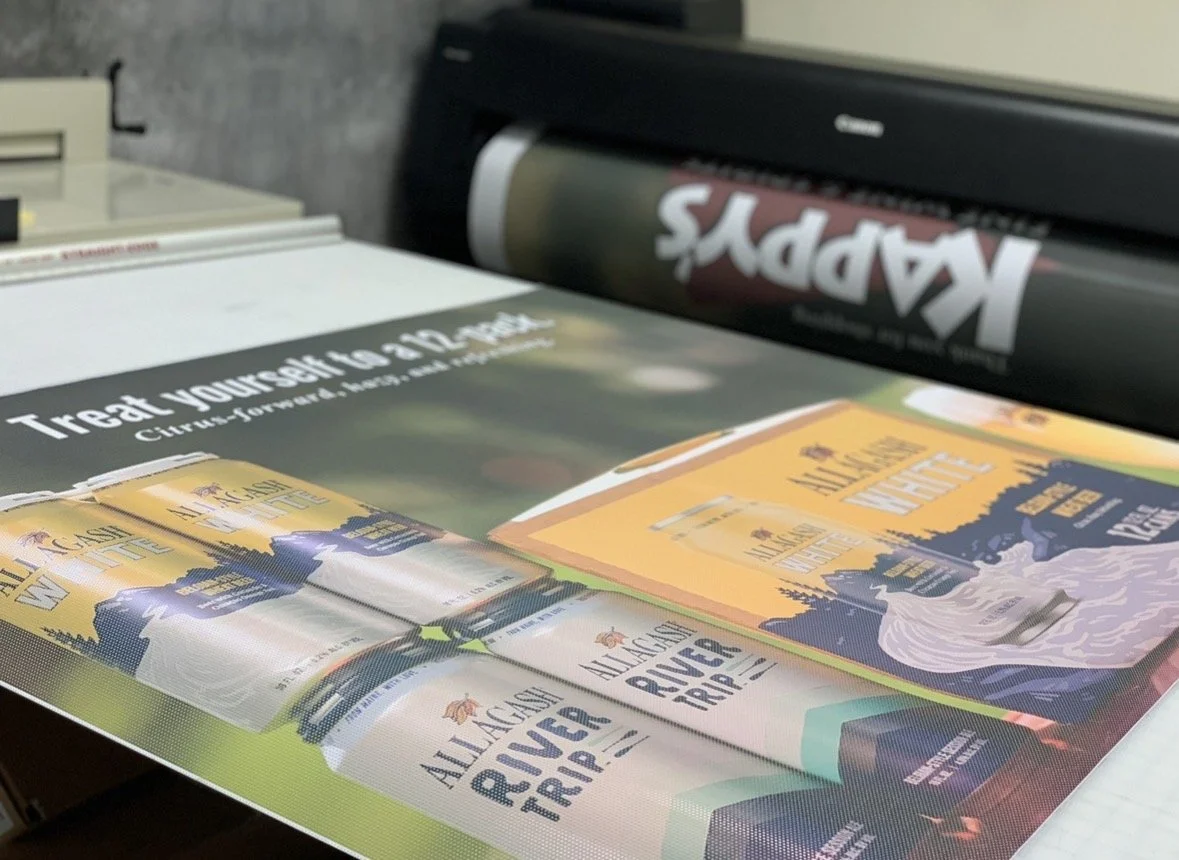 Printed materials promoting Black Arkansas River trips, including a poster with a river scene and a can, and a roll of black vinyl with the word 'KAPPY'S' written on it.