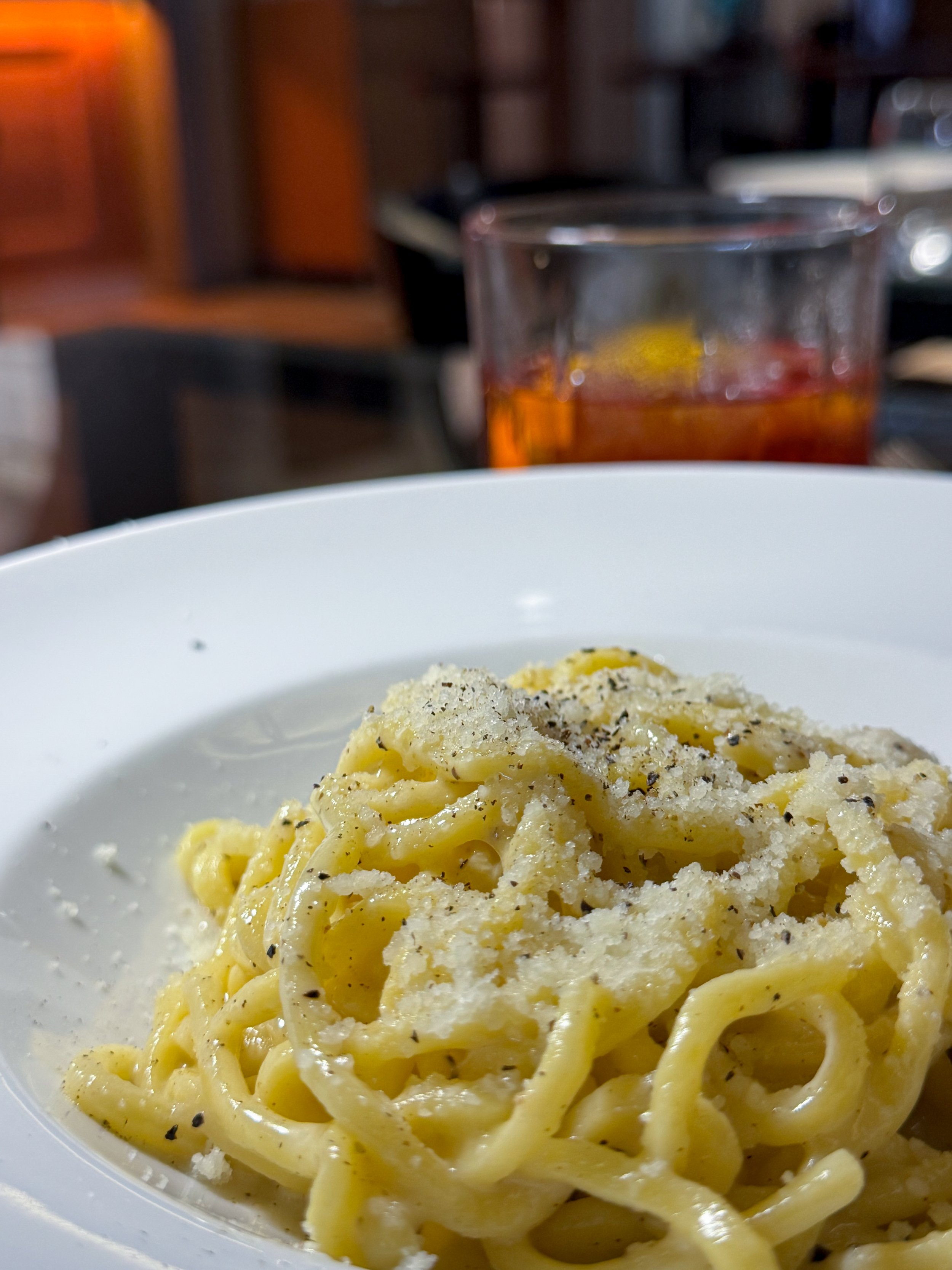 Close-up of a plate of creamy pasta with black pepper and grated cheese.