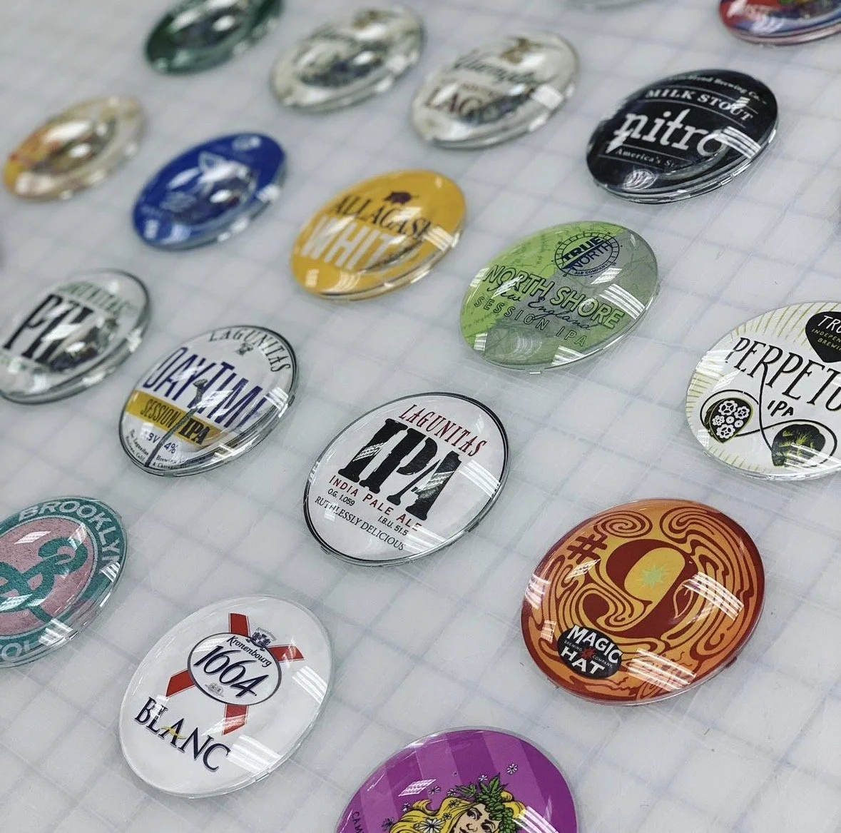 A collection of colorful beer coasters displayed on a clear plastic surface.