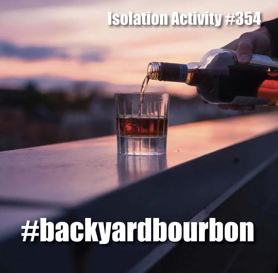 A person pouring a beverage from a bottle into a glass on a table during sunset, with text overlay reading 'Isolation Activity #354' and '#backyardbourbon'.