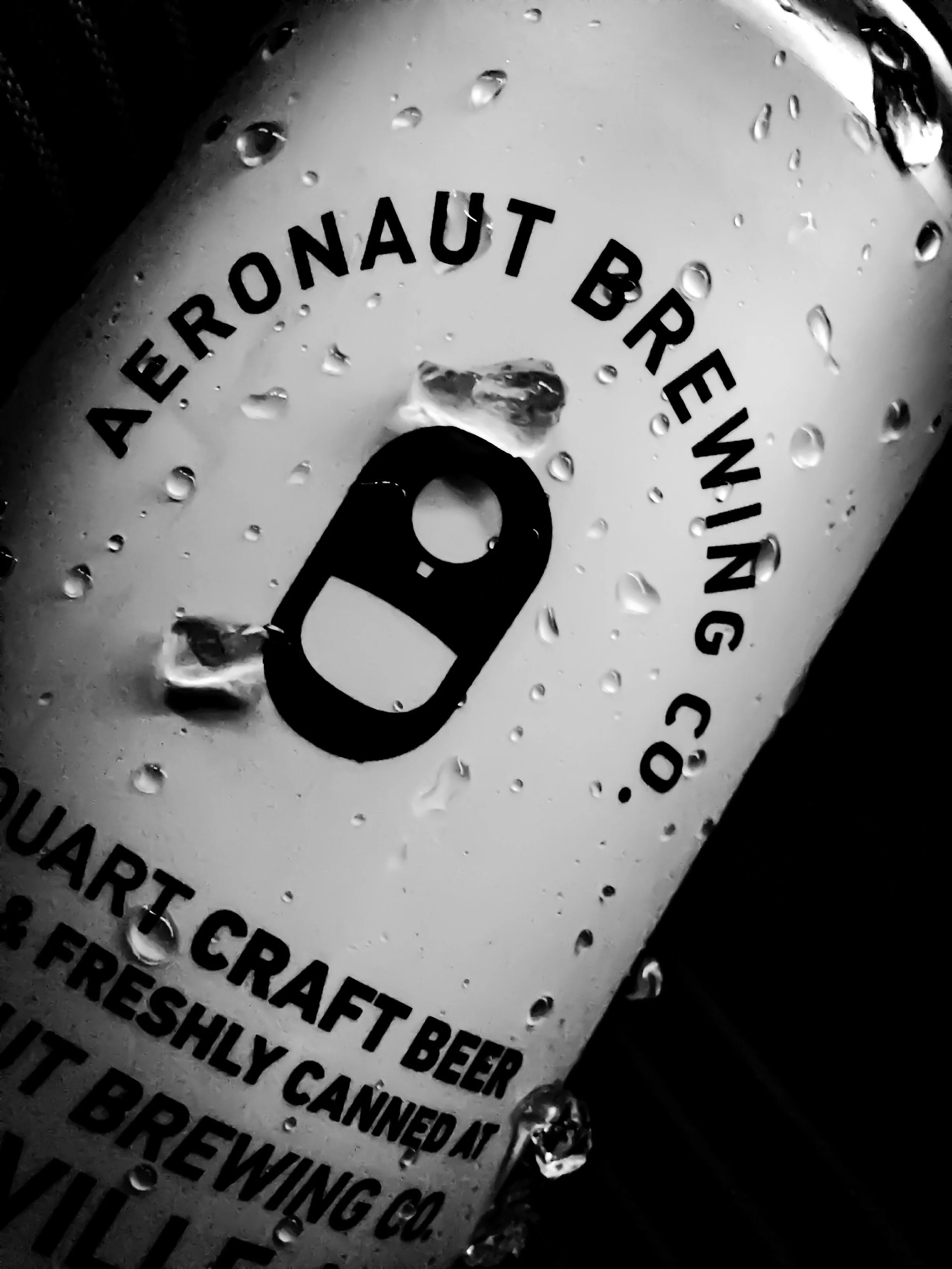 Close-up of a soda can with text about brewing craft beer, with water droplets on its surface.