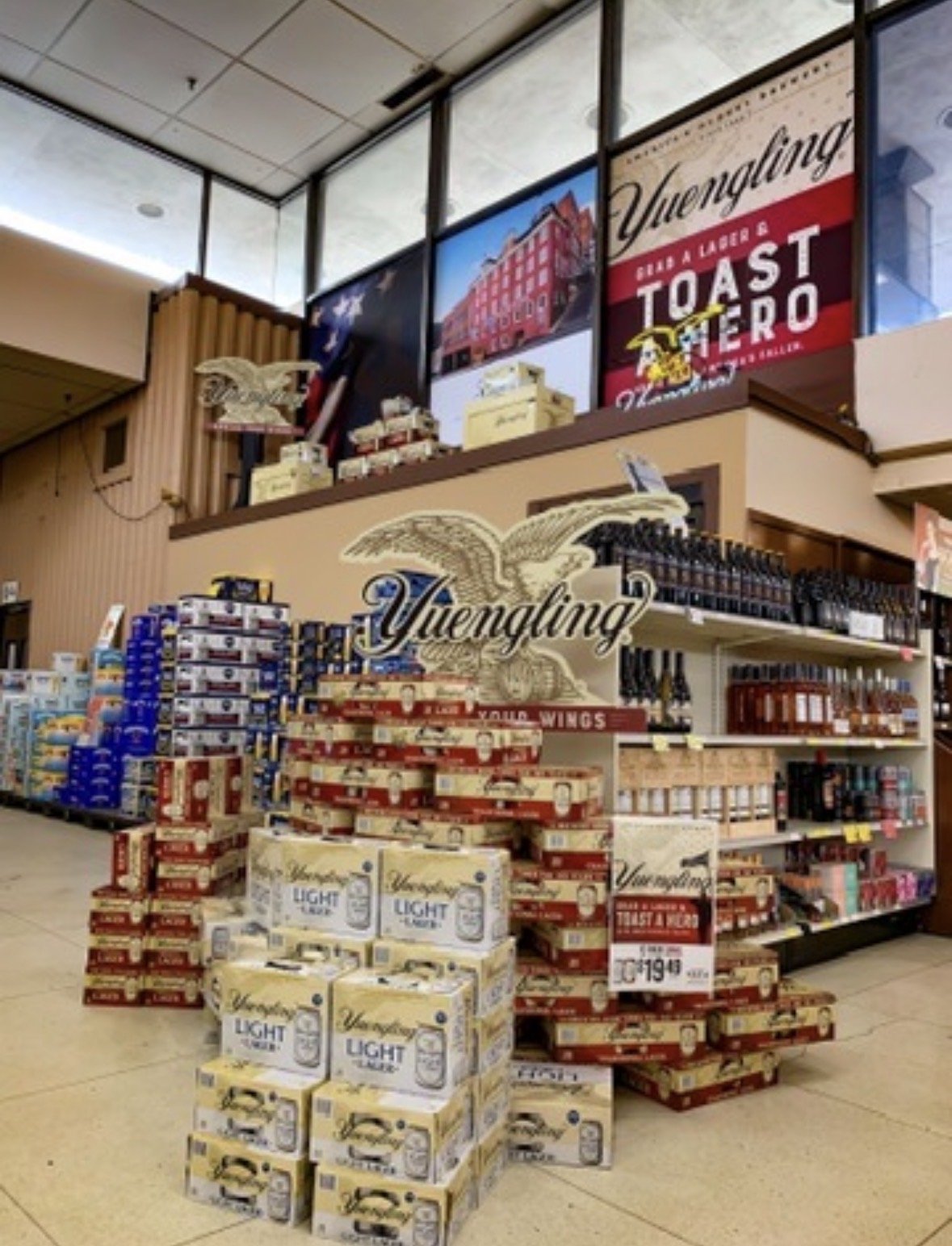 Display of Yuengling beer cases in a store, with signs and promotional banners hanging above.