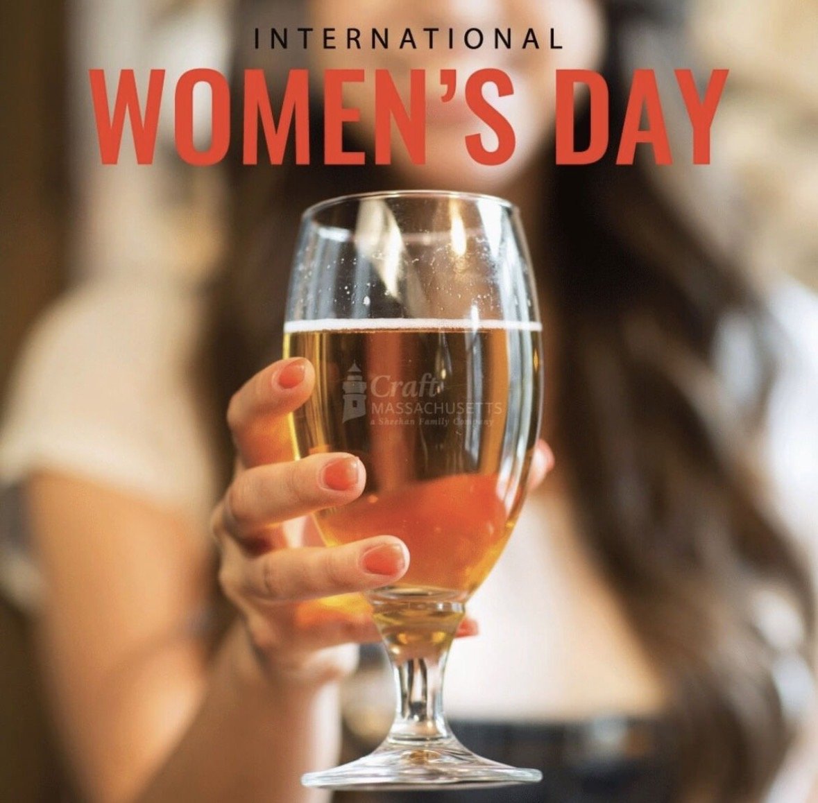 A woman holding a glass of champagne with the text 'International Women's Day' above her in red and black letters.