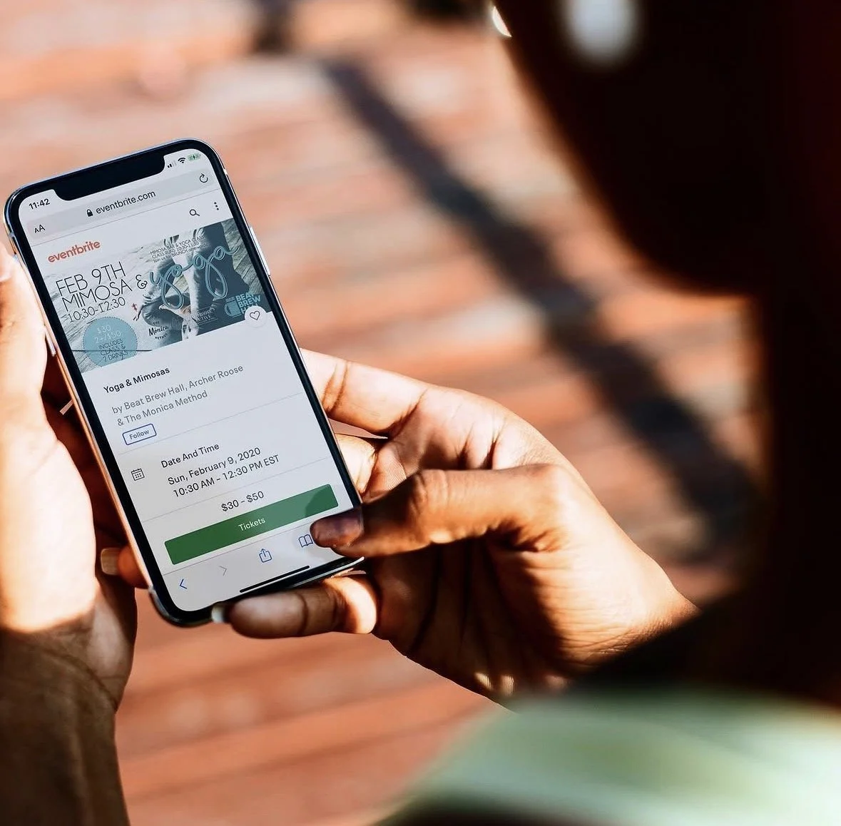 Person holding a smartphone displaying an event ticket for Yoga & Mimosas on an event website.