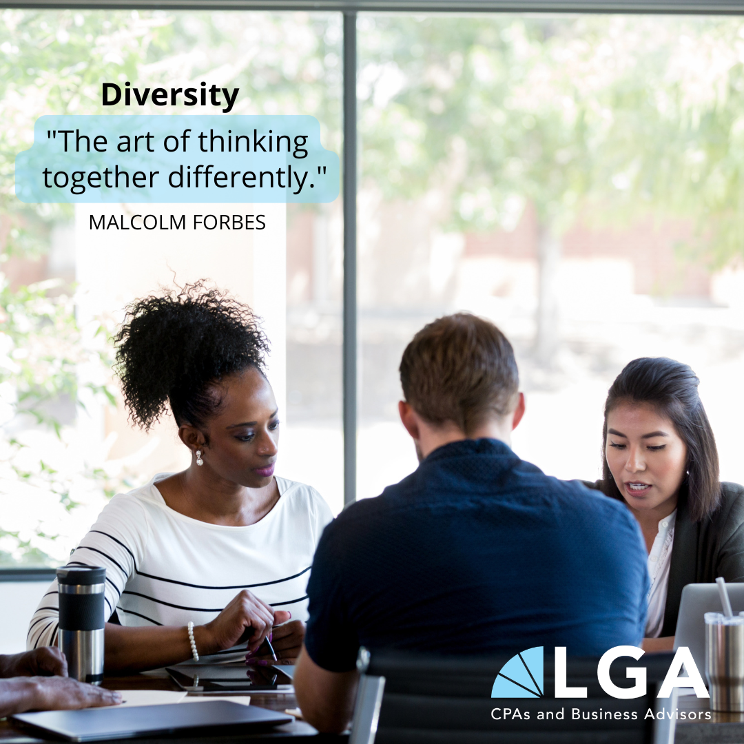 A diverse group of professionals in a meeting room with large windows and trees outside, discussing work, with the quote 'The art of thinking together differently.' by Malcolm Forbes.