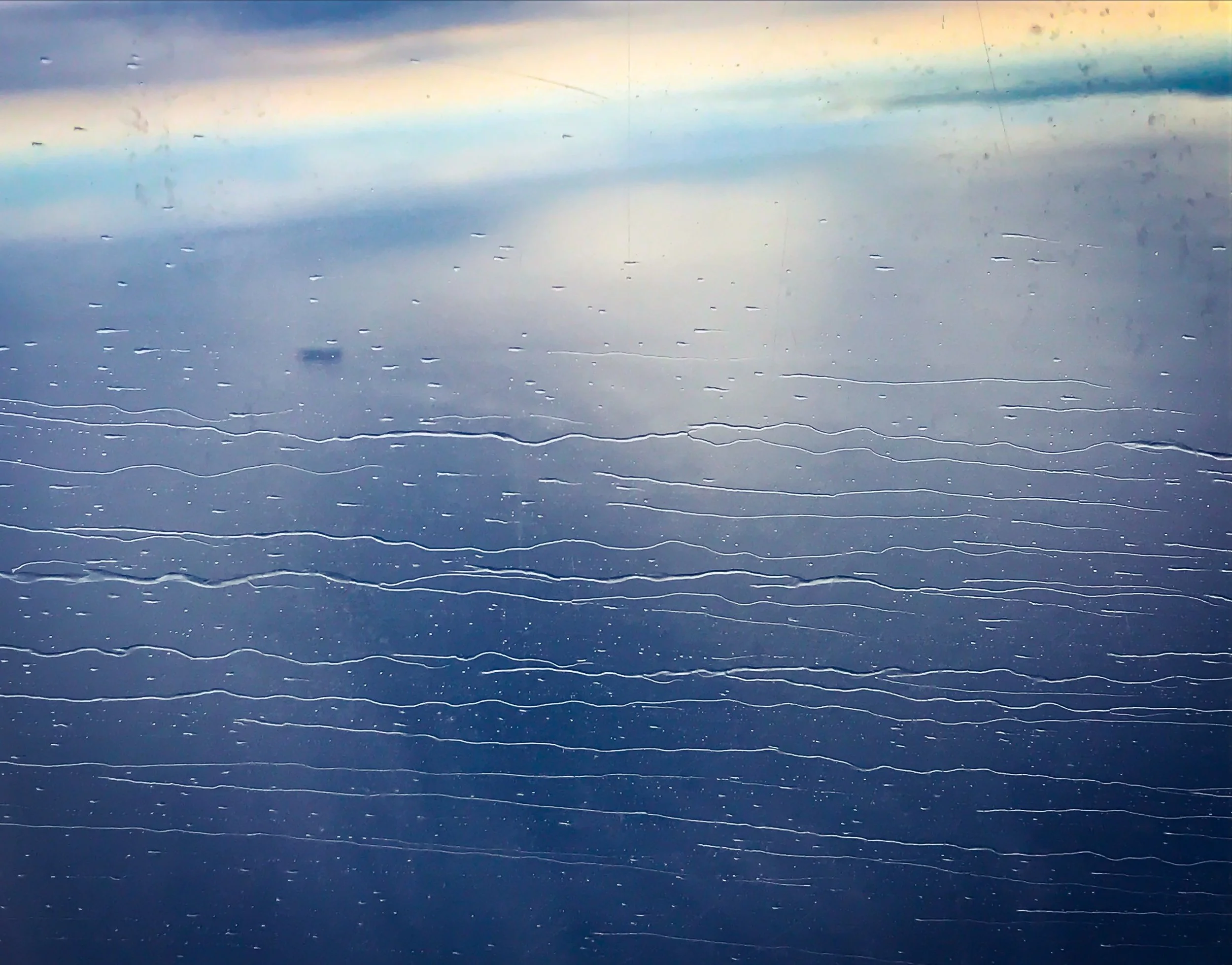 View of a cloudy sky with raindrops on a window or surface.
