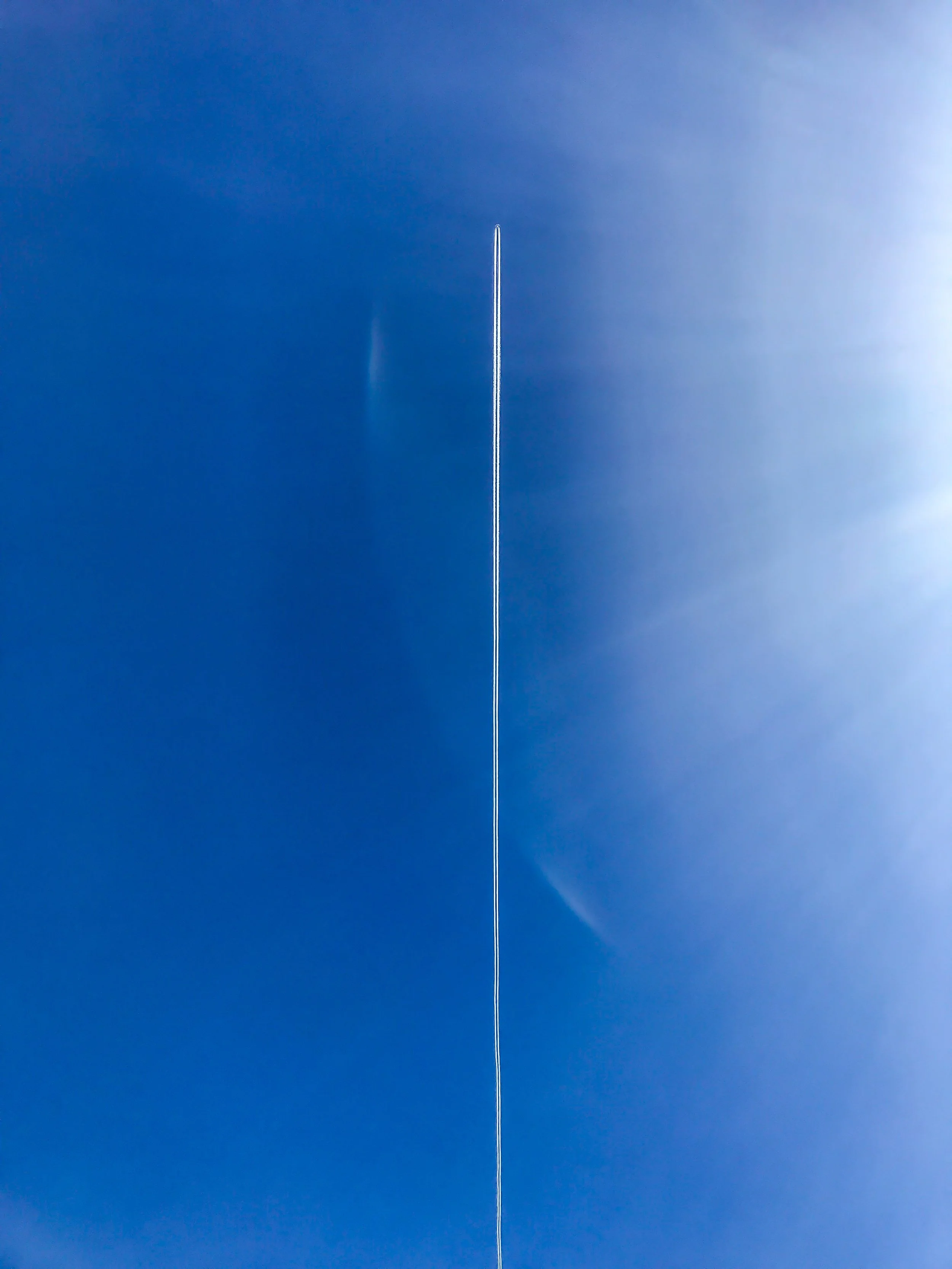 Clear blue sky with a jet airplane flying at high altitude, leaving a thin trail behind.