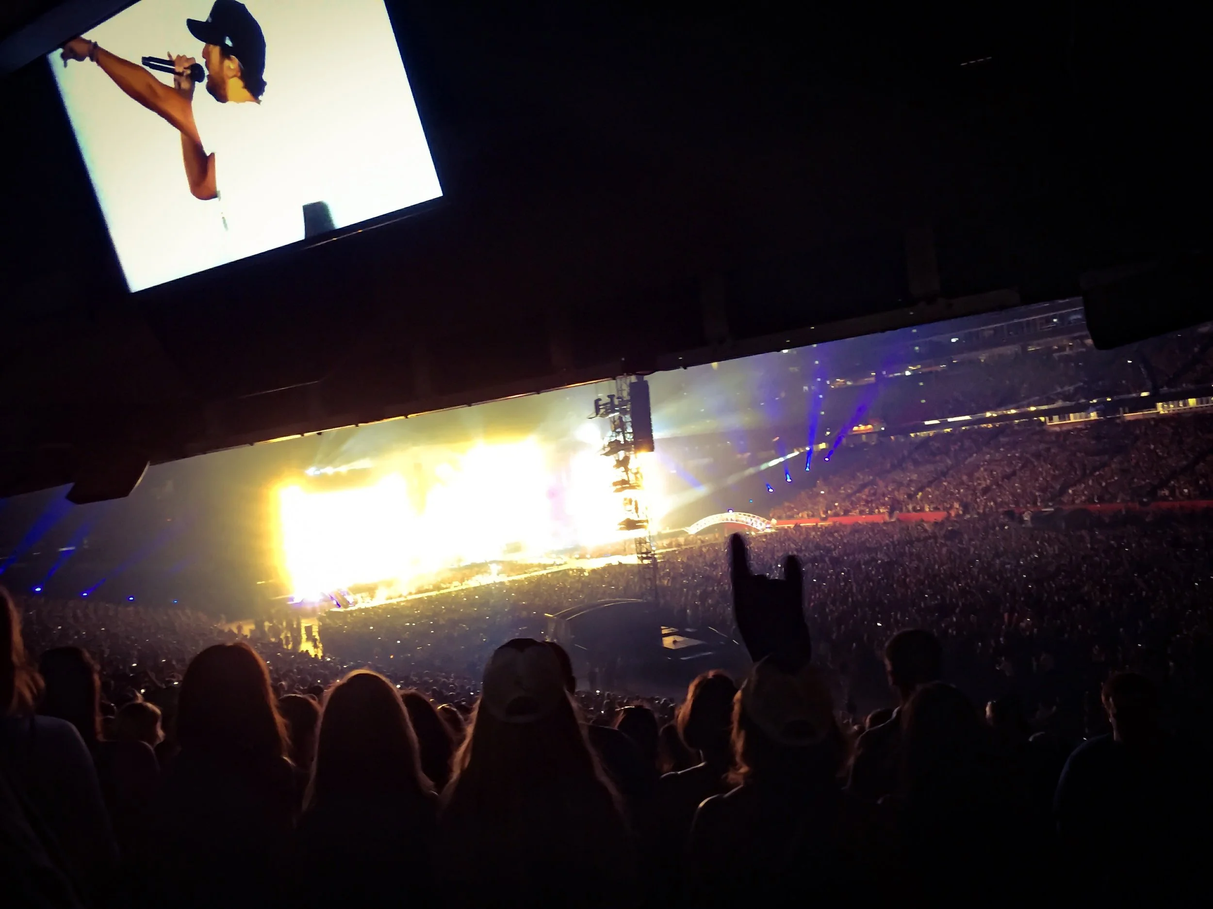 A large crowd watching a concert with bright stage lights and colorful effects.