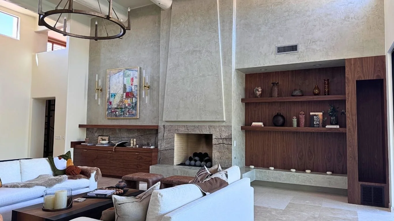 Great room with high ceilings, a full-height stone fireplace and built-in wood shelving.